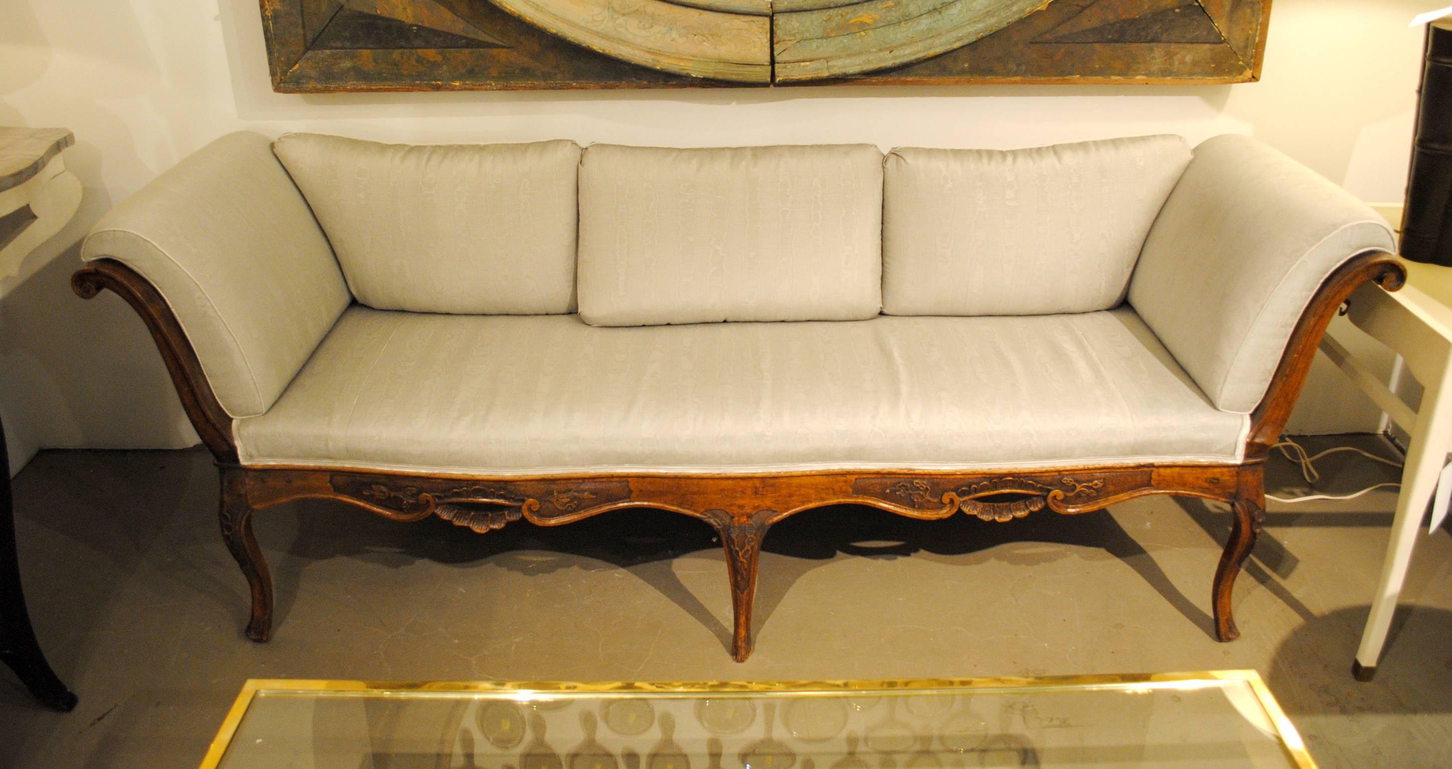 A carved Italian gondola sofa with well executed scrolled arms and a decoratively carved apron. Later 20th century back added. Covered in Marvic Misa Moire fabric.