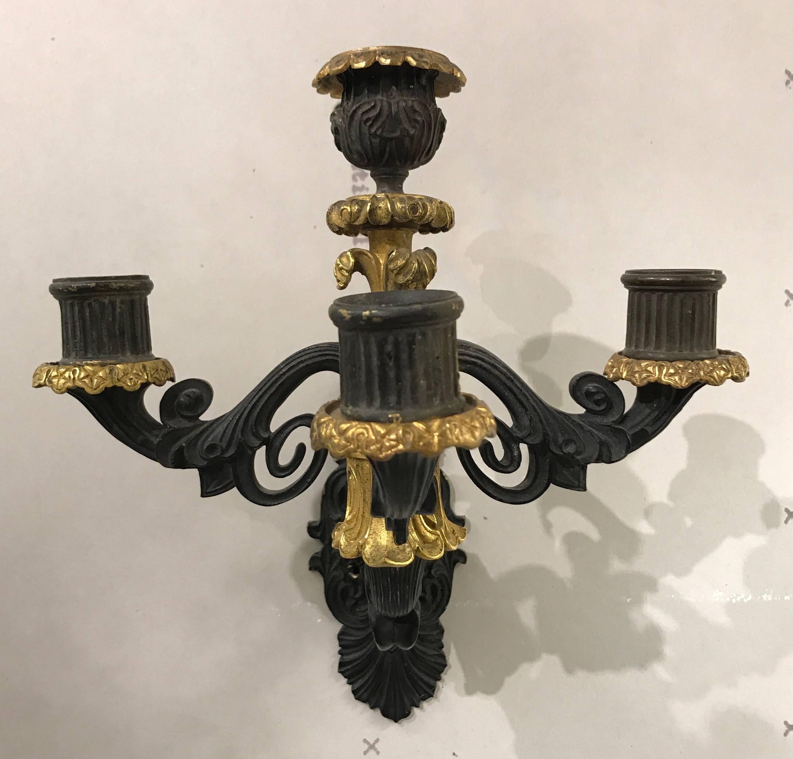Pair of four-arm black and gilt bronze sconces with scrolled arms and decorative backplates. Drilled for wiring.