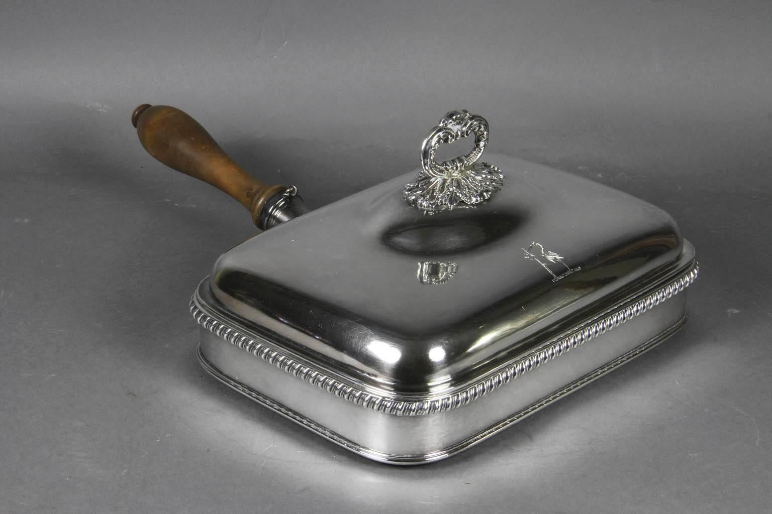 Typical form rectangular with hinged removable domed lid with engraved crest and cast loop finial, wood handle unscrews expose fill hole for hot water to be poured into conforming dish form base. Provenance: James Robinson NYC, Auchincloss family,