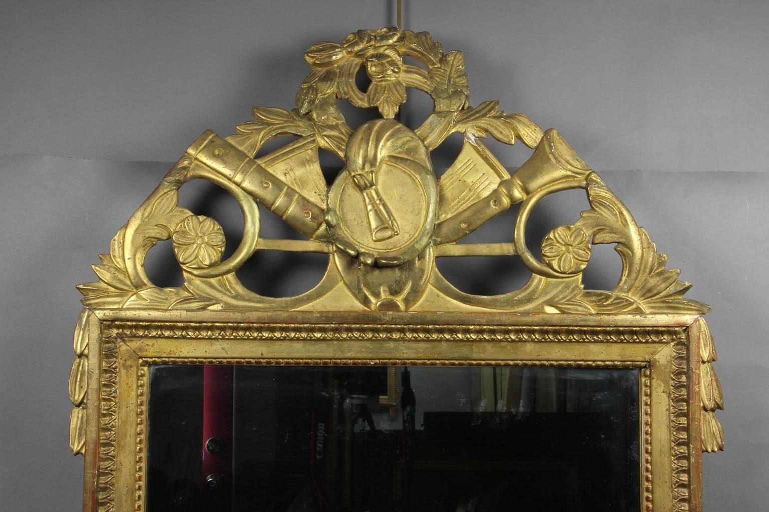 The arched cornice with musical trophy decoration over a beaded and leaf tipped frame.