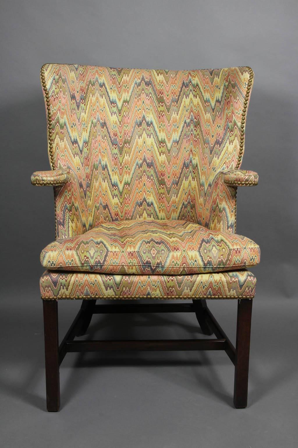Upholstered in a Bargello style fabric with brass tacks, loose cushion, barrel back, raised on square legs with splayed rear legs.