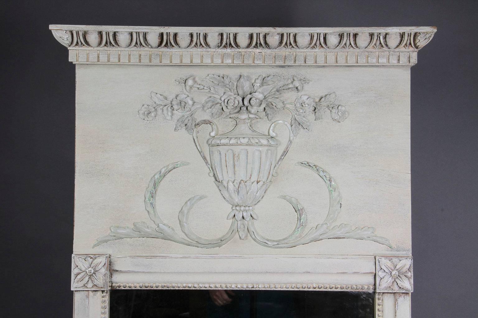 Rectangular with urn and floral crest above the mirror plate, frame beaded an rosette corners.