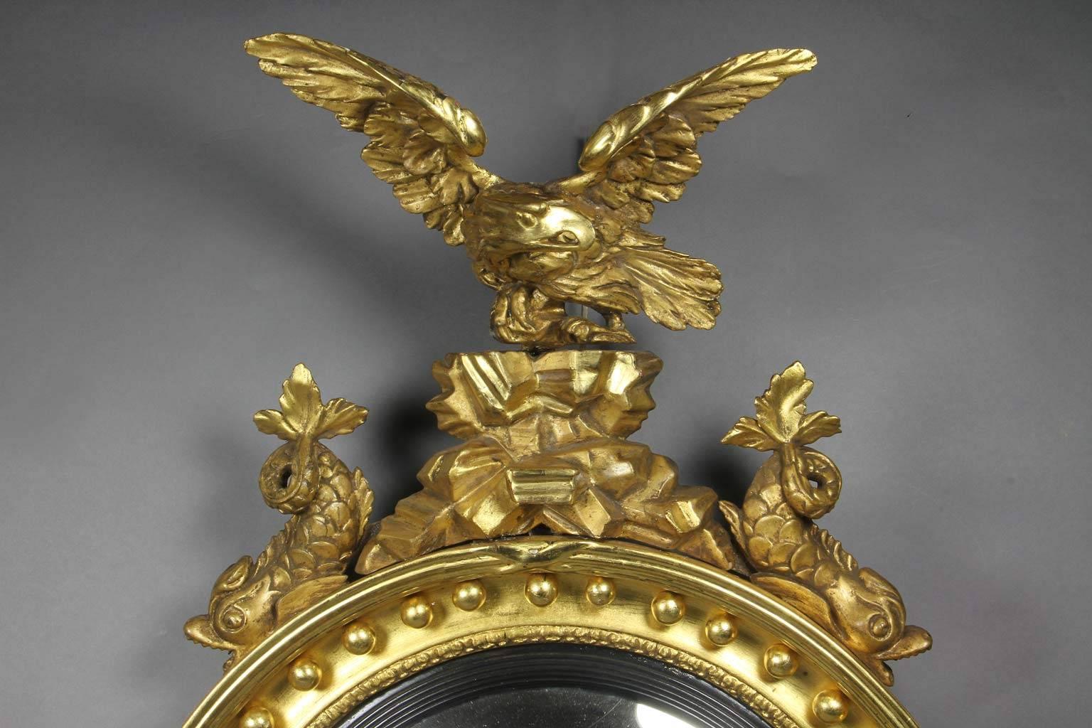 With eagle on rockwork flanked by dolphins over a convex glass plate set within a conforming frame with spherules and ebonized inner band, base with acanthus leaves.