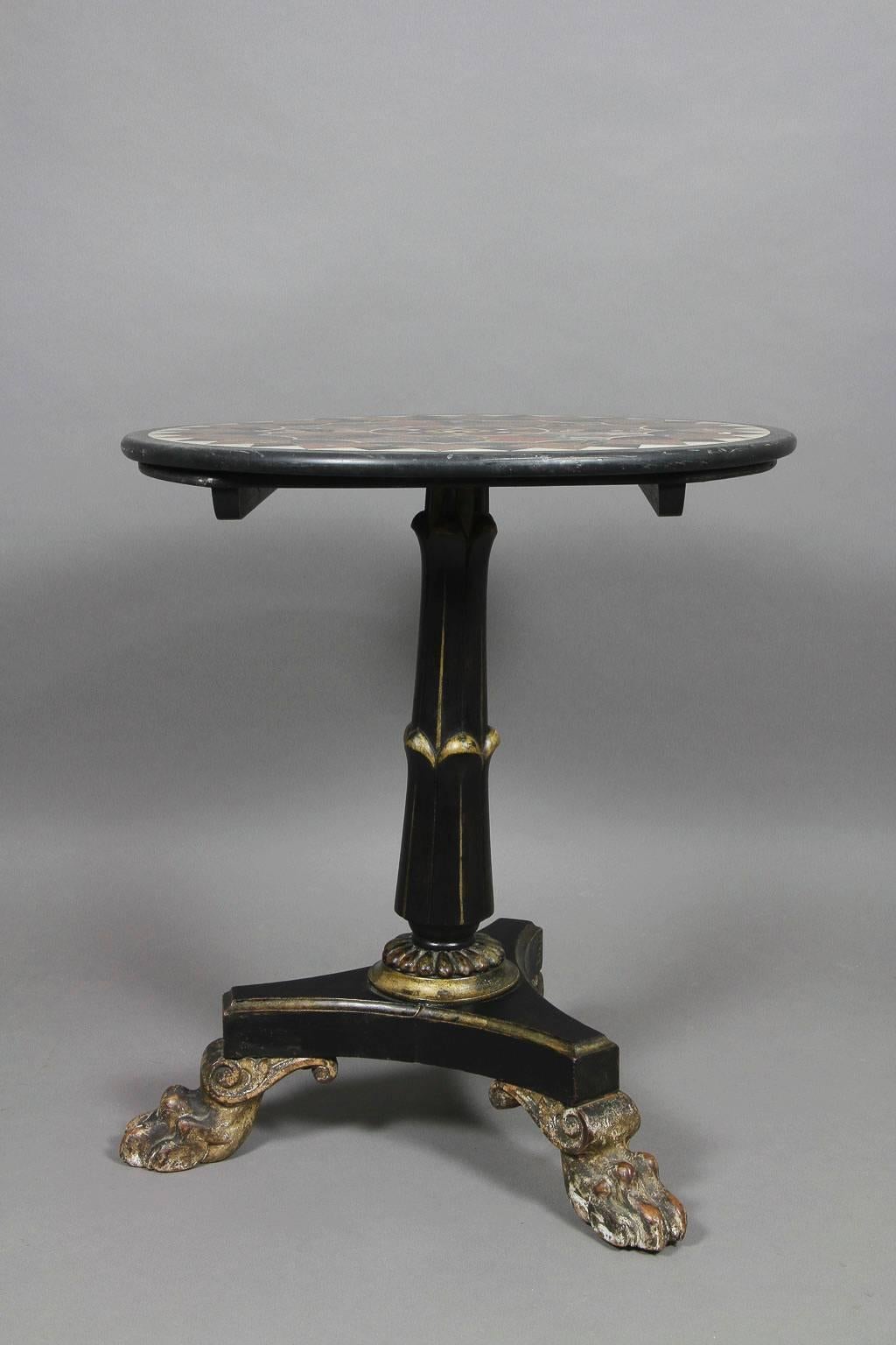Circular top with various stone inlays on a tapered support with lotus carving ending on a tripod base with lions paw feet. The table is period but reduced in height.