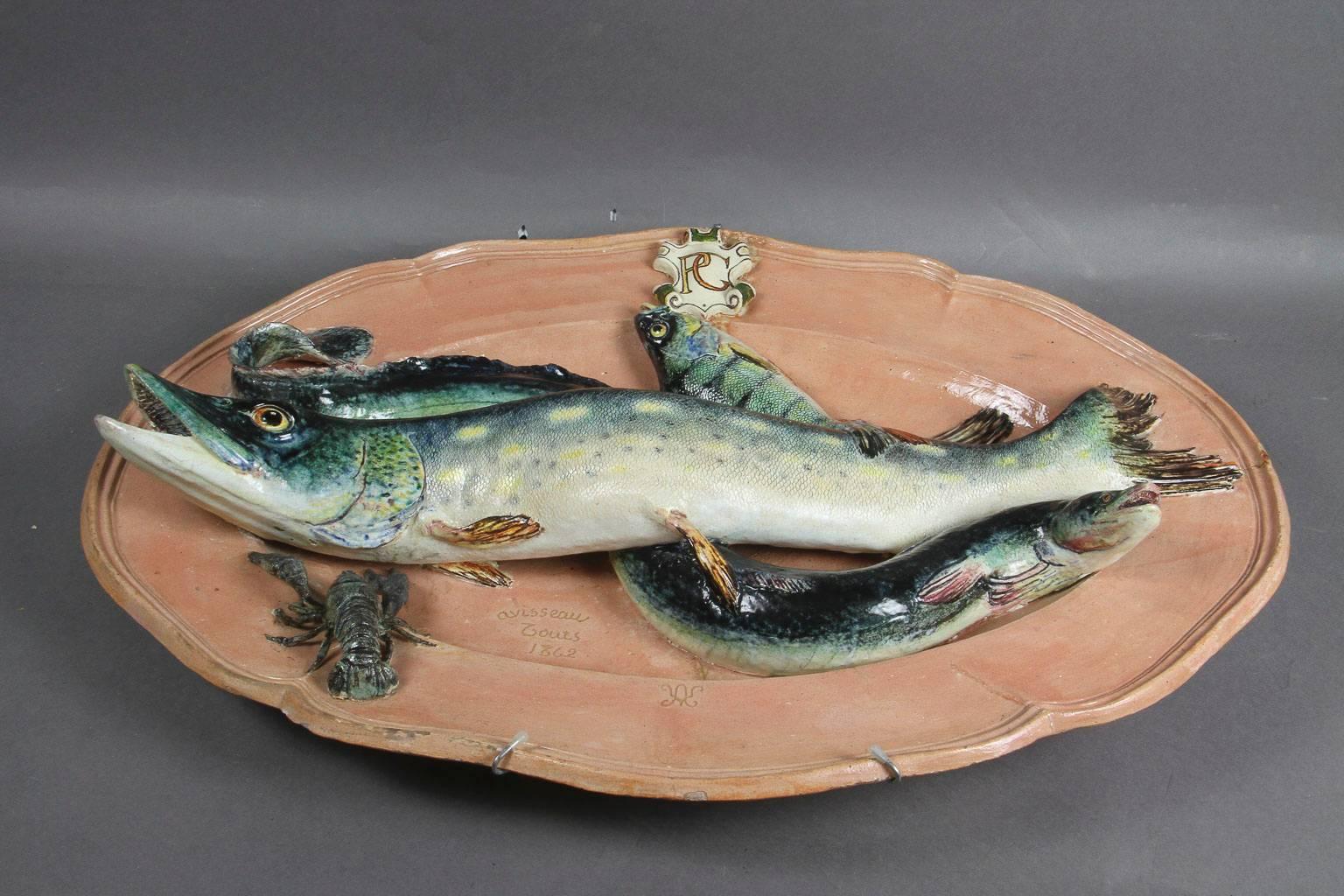 Large platter with crest and initials PG, decorated with a pike, eel and a crayfish. All on a peach colored platter. Signed.