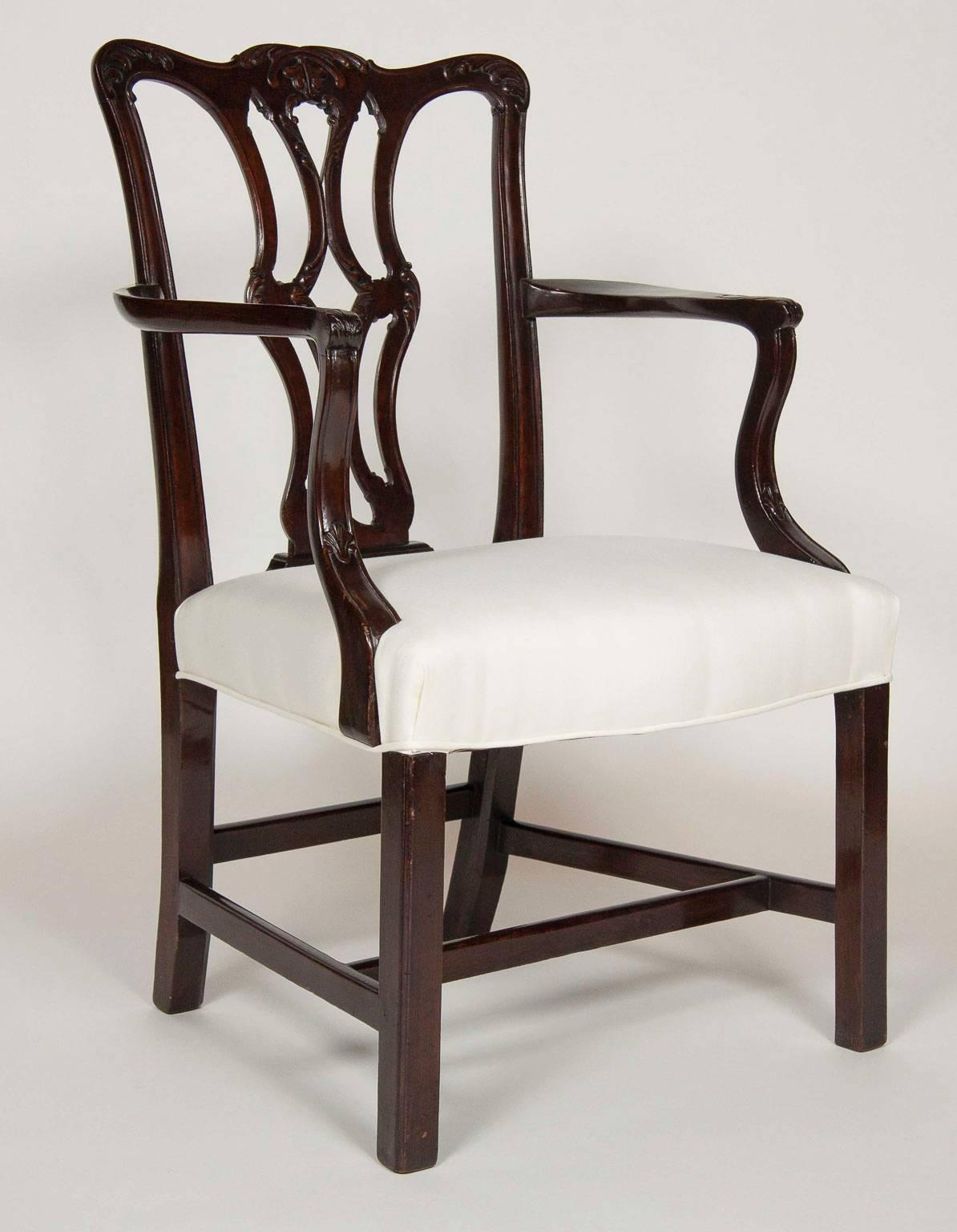 Each with a serpentine crestrail over a pierced carved splat, bowed seat raised on straight square legs with box stretchers. Comprising a pair of armchairs.