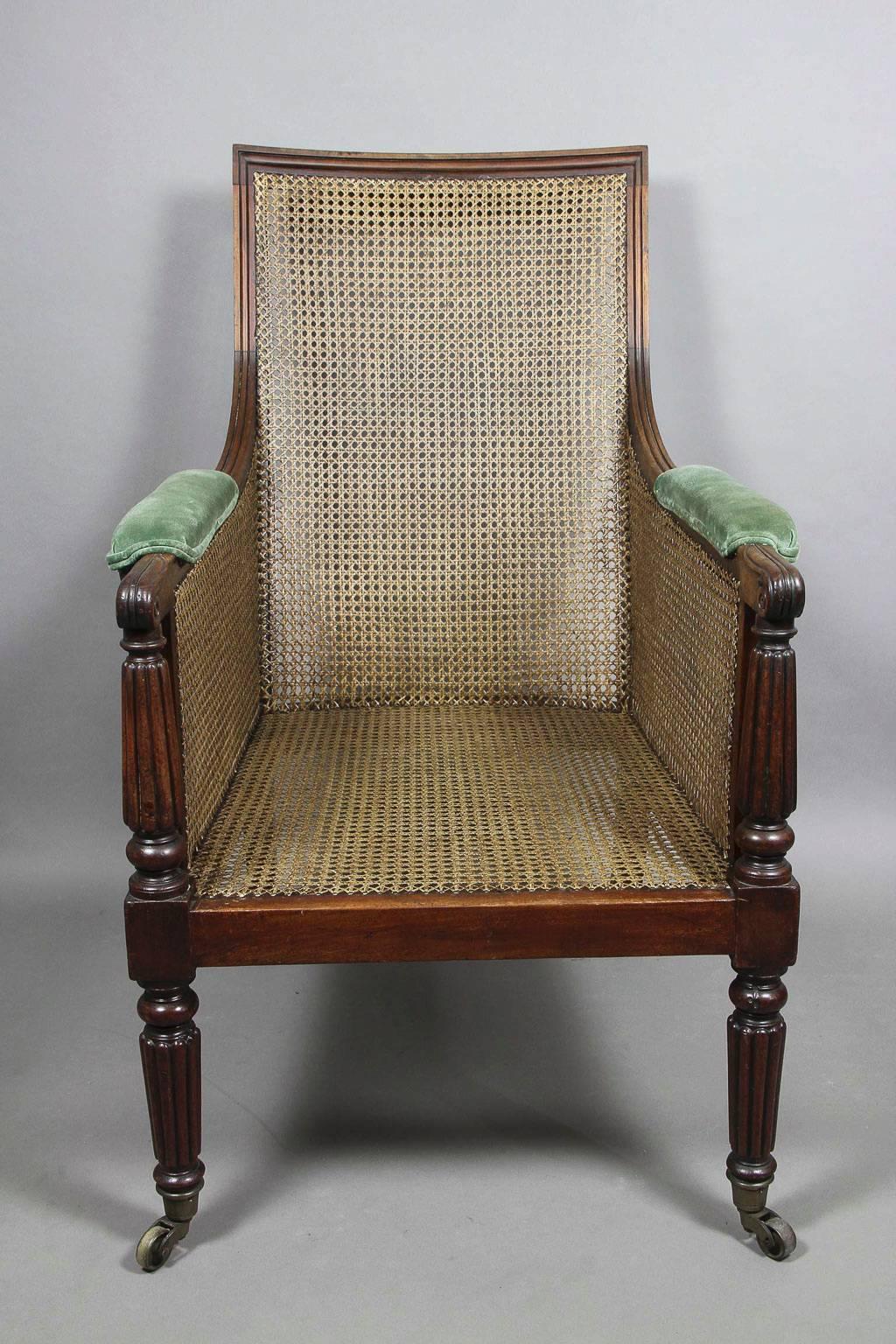 Rectangular molded and reeded frame, all newly caned, down swept arms with lotus leaf carved ends supported on reeded supports, raised on reeded tapered legs and casters.