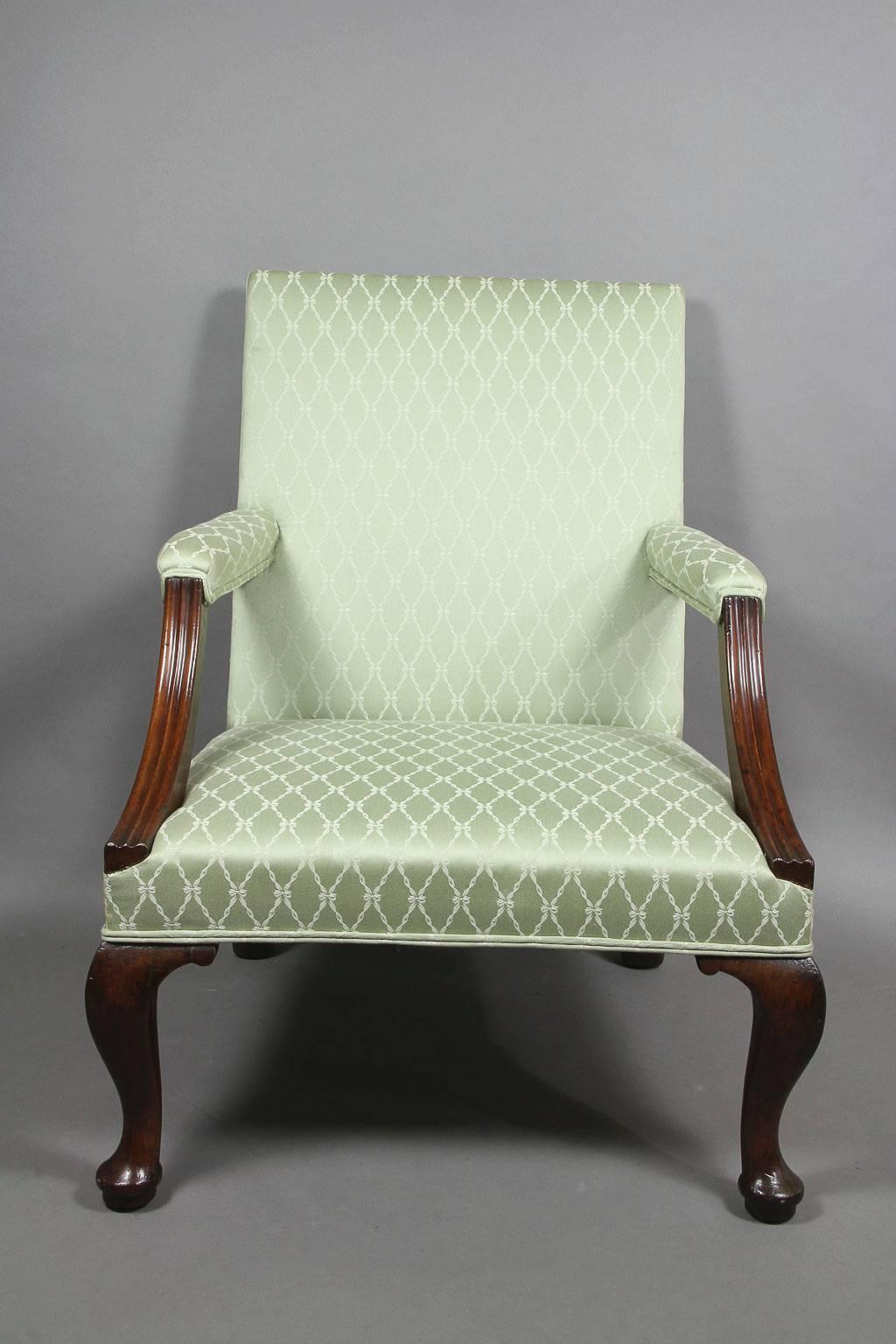 Square upholstered back and reeded downswept arms, straight seat and raised on cabriole legs ending on pad feet.