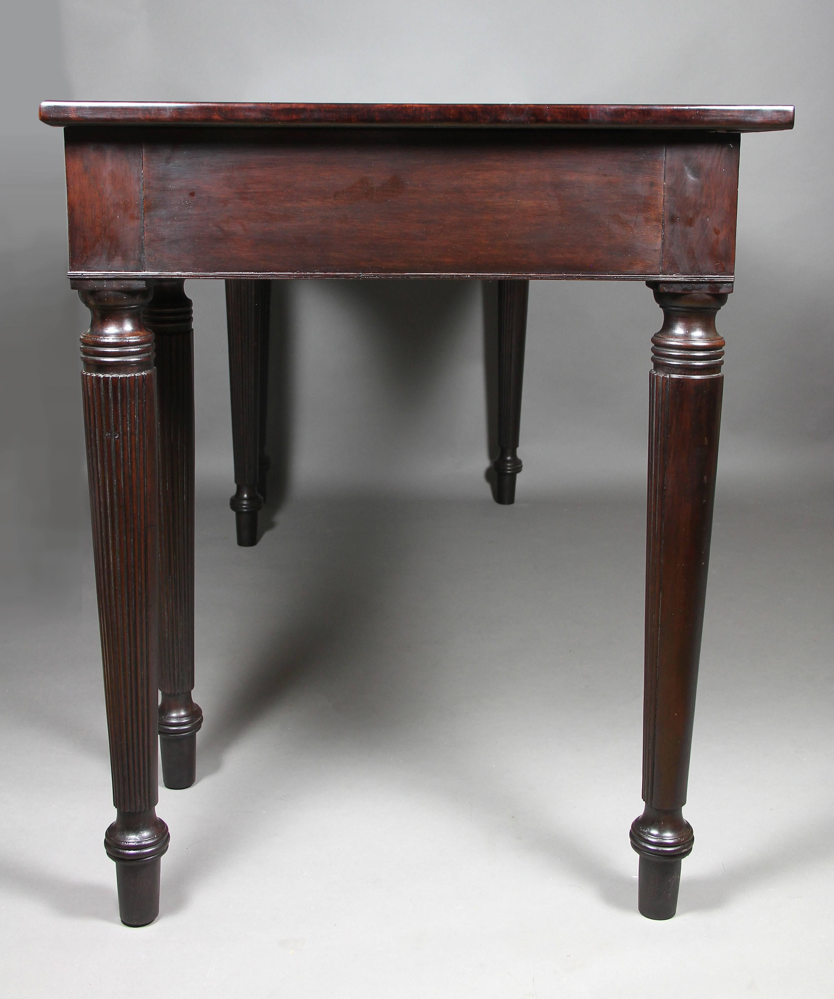 Rectangular top with concave mid section over a conforming frieze with three drawers and horizontal carved reeded decoration raised on circular tapered reeded legs and toupie feet.