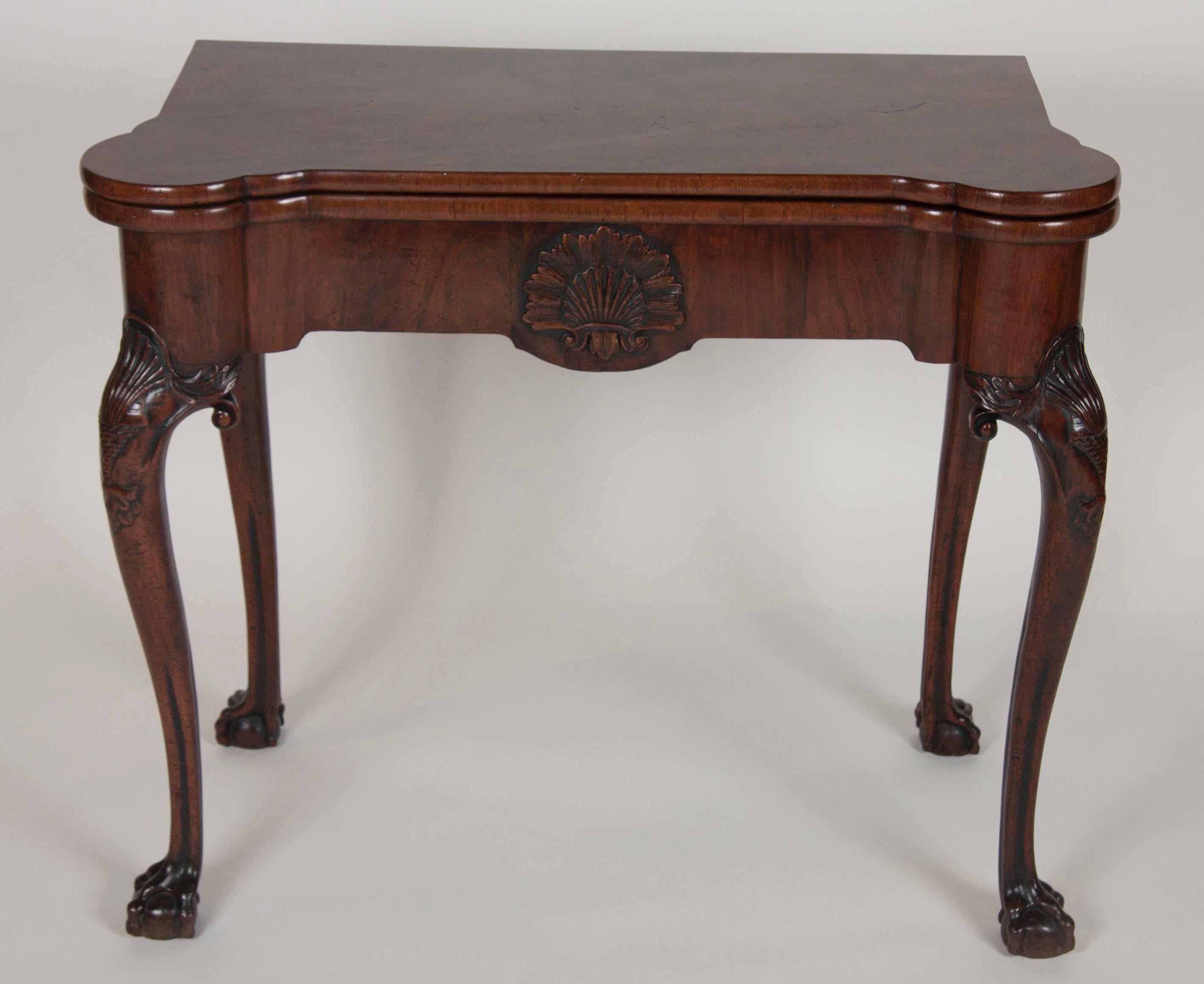 A fine walnut George I period table with a central shell carving and concertina opening action. Turreted top corners over a central carved shell, carved shell cabriole legs molded and ending on ball and claw feet.