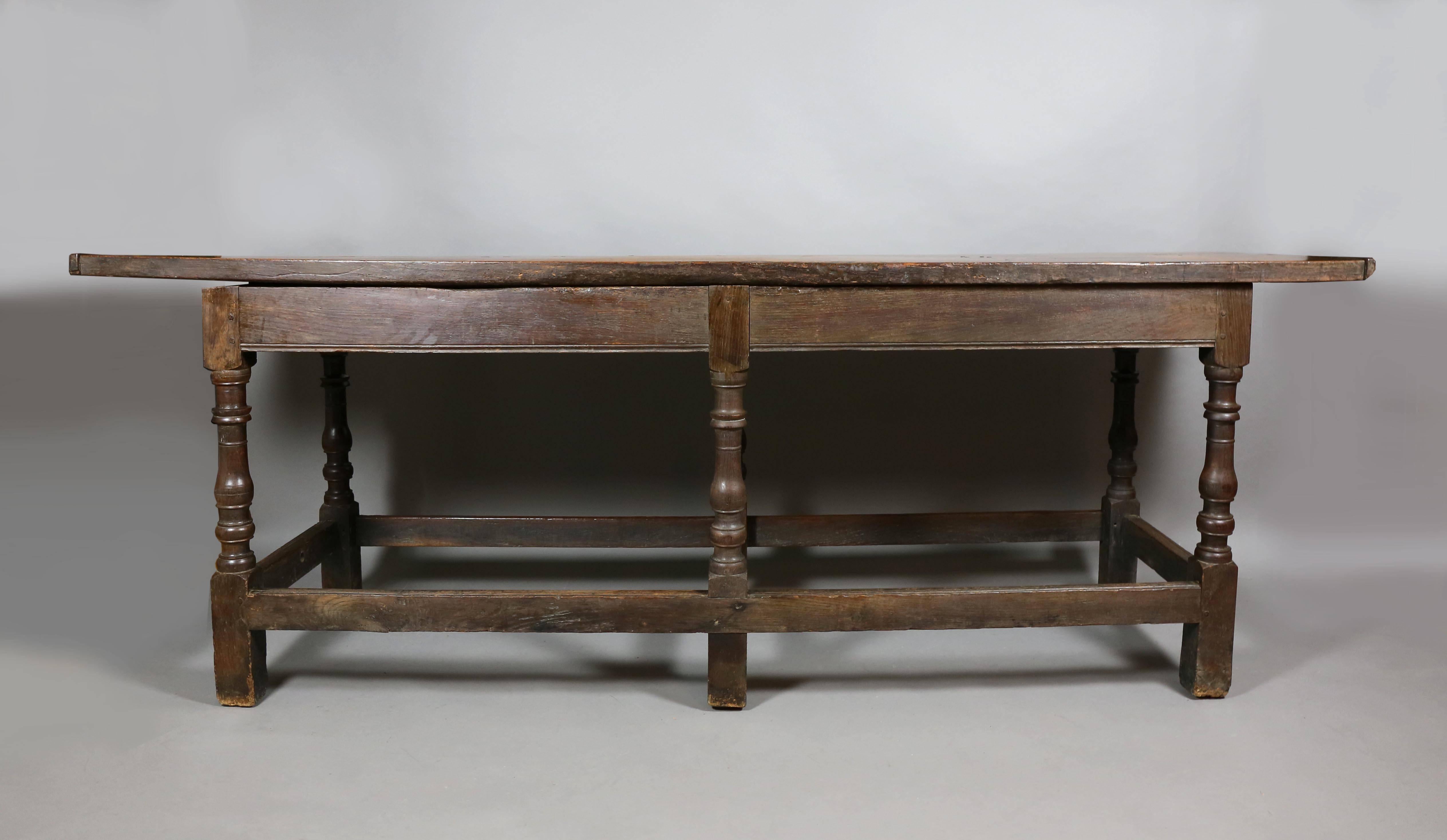Two board top with battened ends over a plain frieze raised on turned legs, joined by stretchers on square feet. Top has beautiful waxed patina.