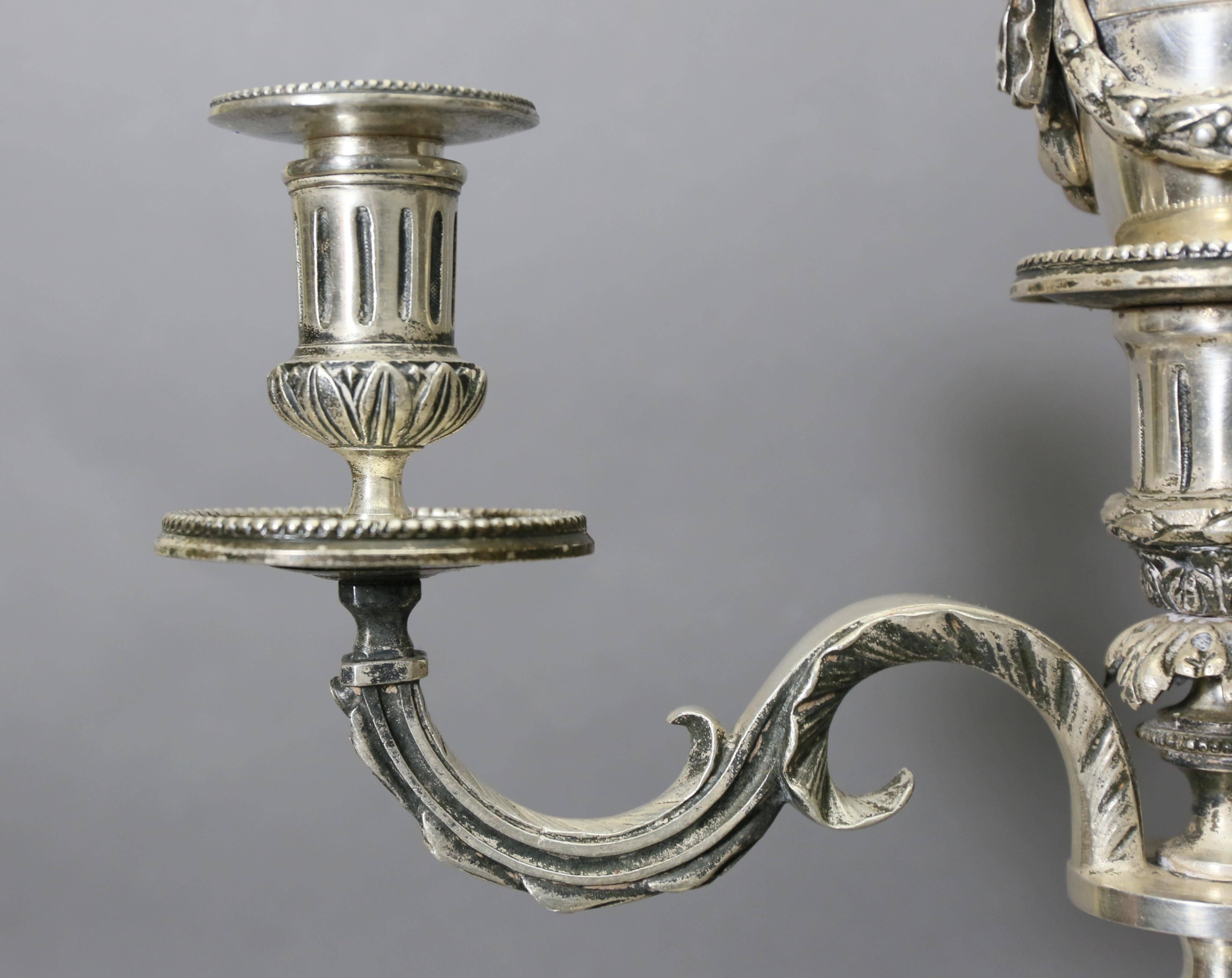 Each candelabra has intricate details of bows, leaves, and cording with tassels; with one bow missing from the back side. 

Candelabra were previously lamped.
