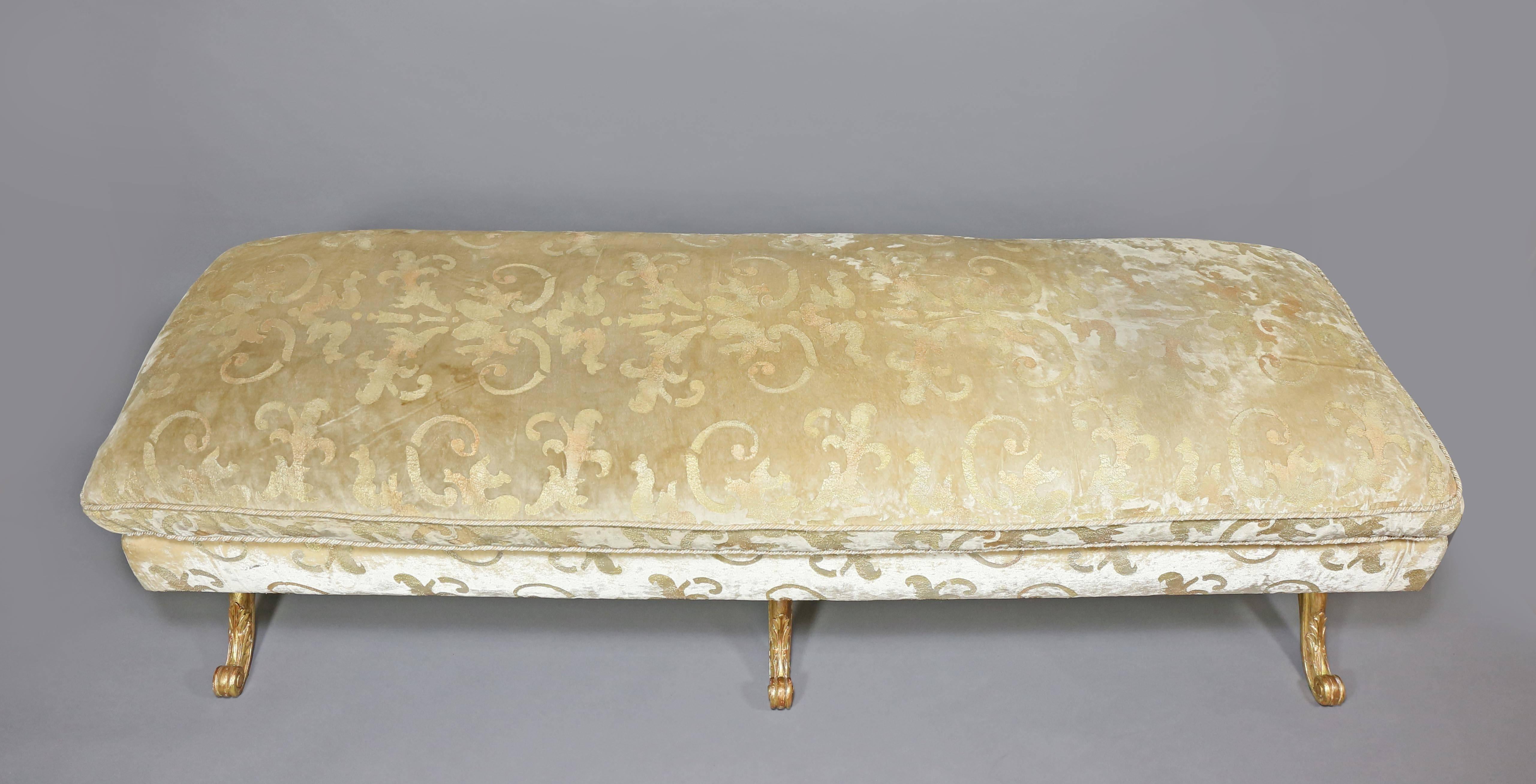 Rectangular with cushioned seat raised on carved X-form legs with central carved rosette joined by a turned stretcher, with scroll feet. The gilding is in excellent condition. The fabric on the base section of one is in poor condition on the