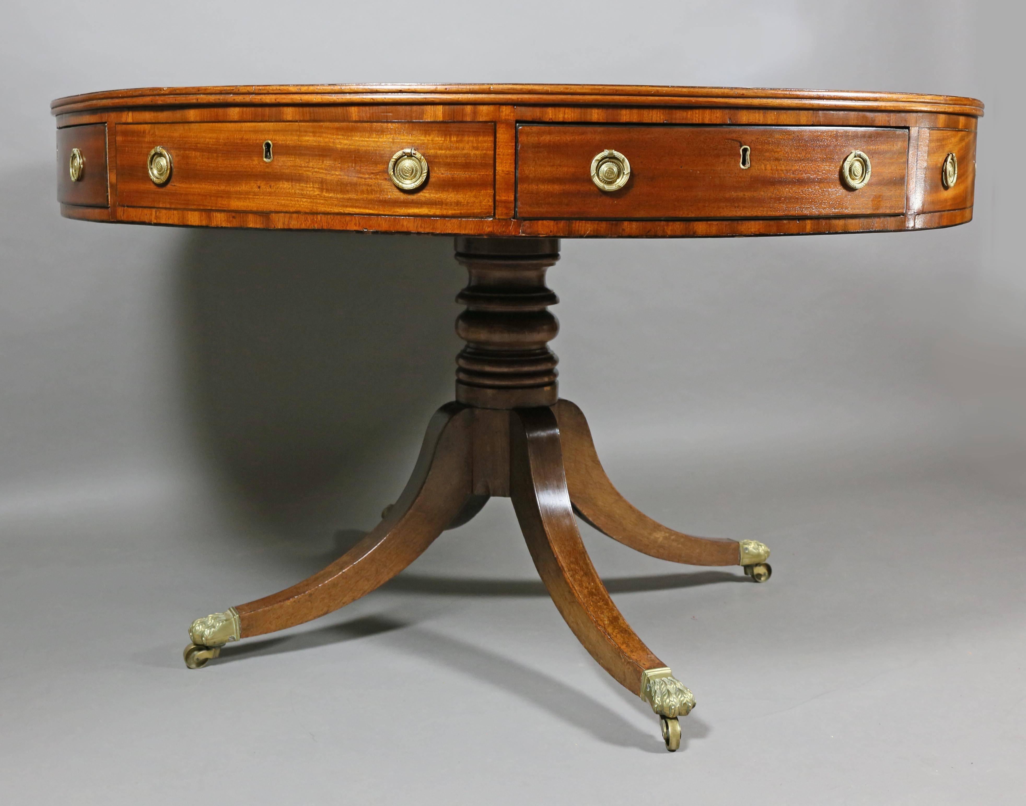 Circular inset blackish blue leather top over a series of false and working drawers raised on a ring turned support and four saber legs ending in paw from cup casters.