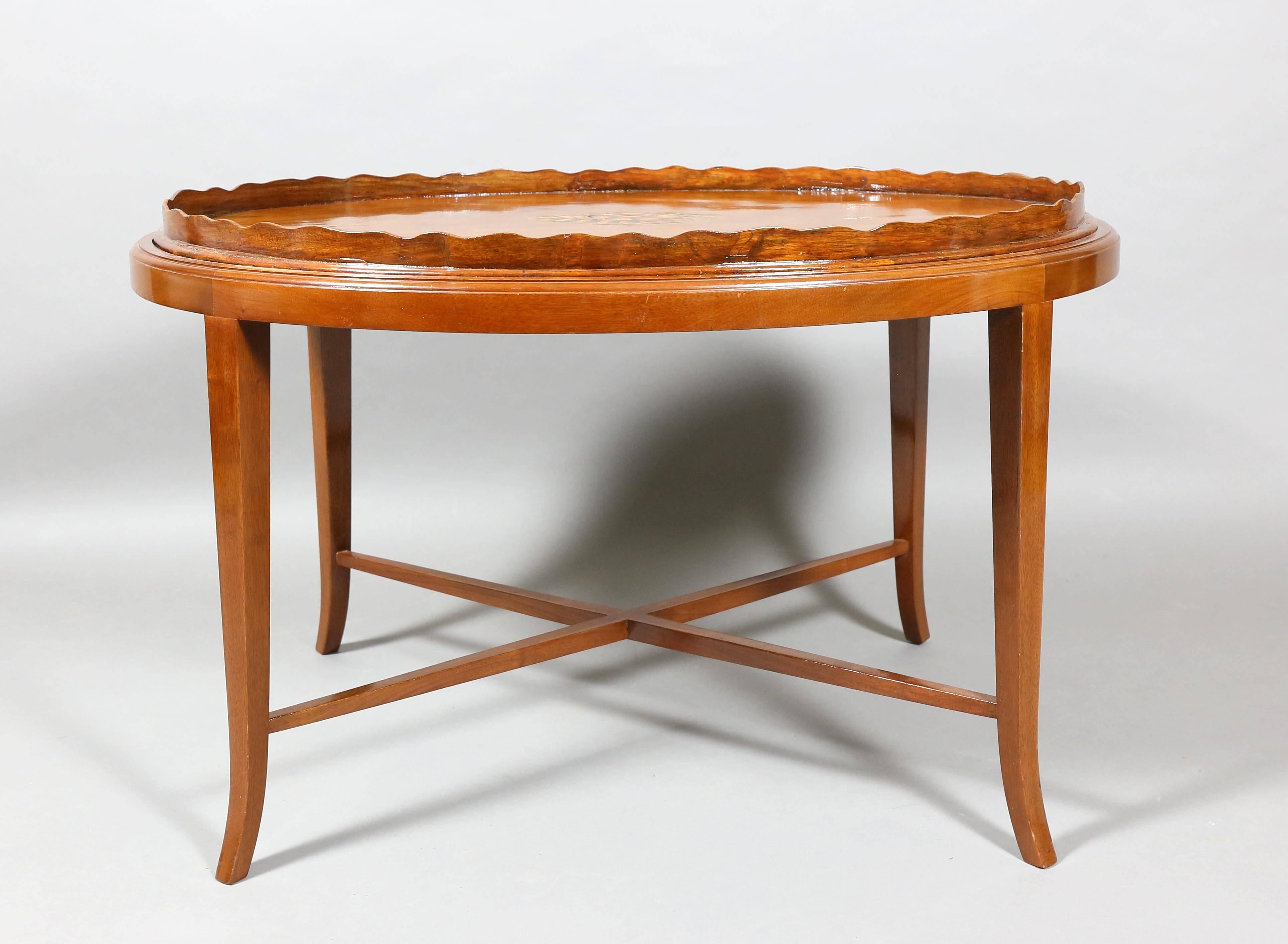 The tray oval with serrated edge with central inlaid shell raised on square tapered legs with X-form stretcher.