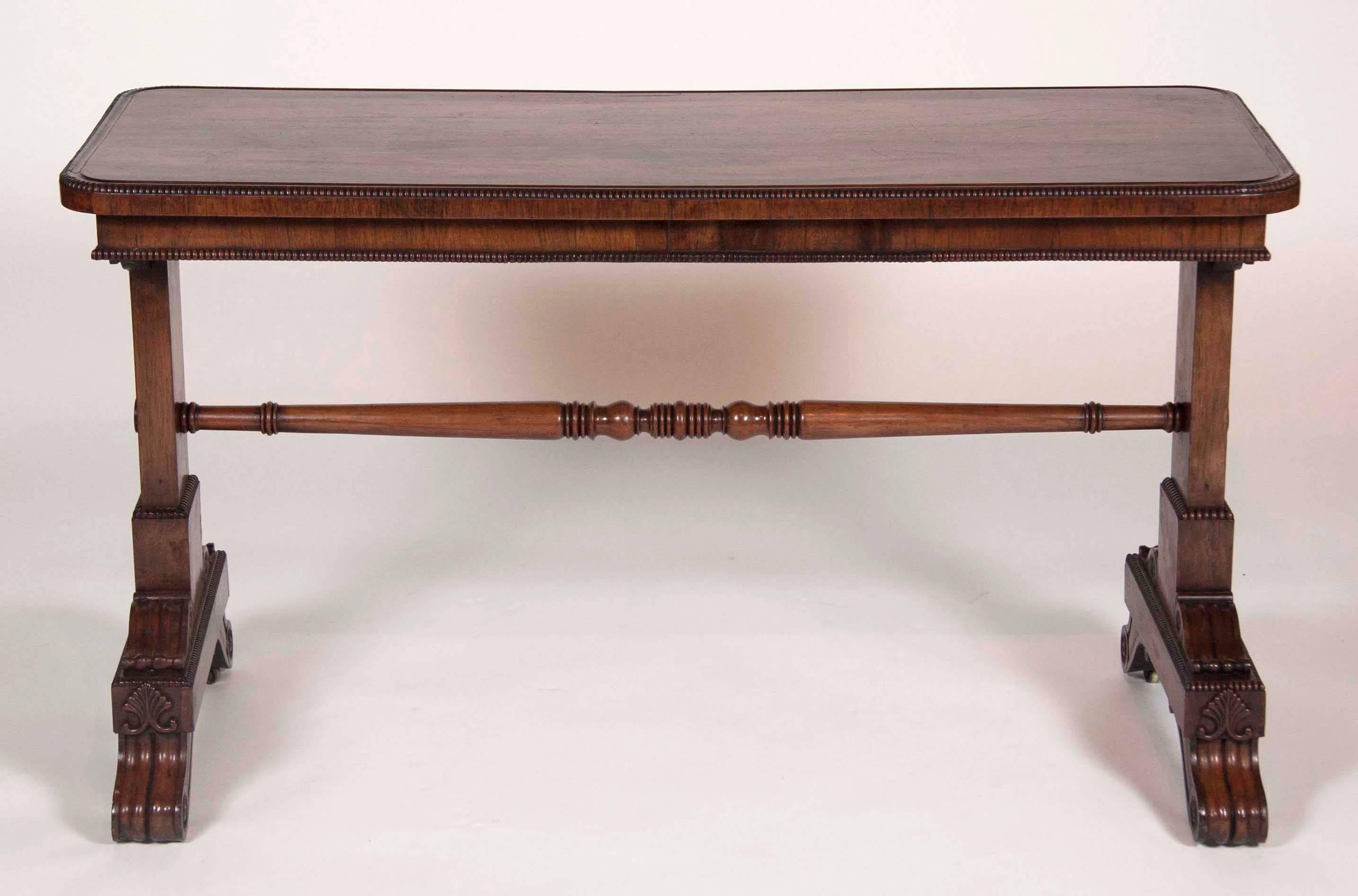 Rectangular top with carved beaded edge with a plain frieze over a trestle support and turned stretcher raised on carved scrolled feet.