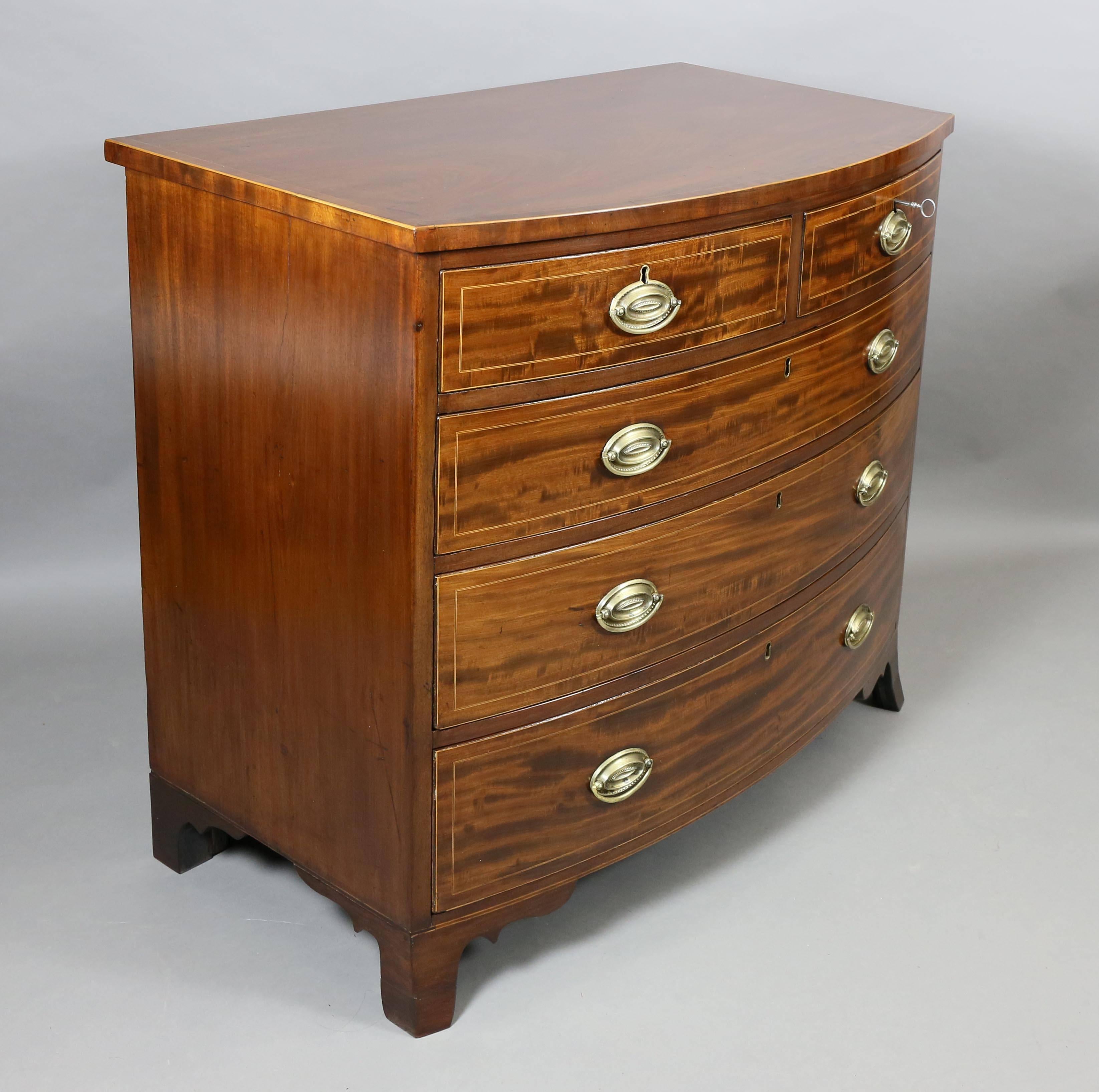 Rectangular bowed top with mahogany crossbanded edge over a pair of drawers over three graduated drawers all with string inlay, raised on splayed feet.