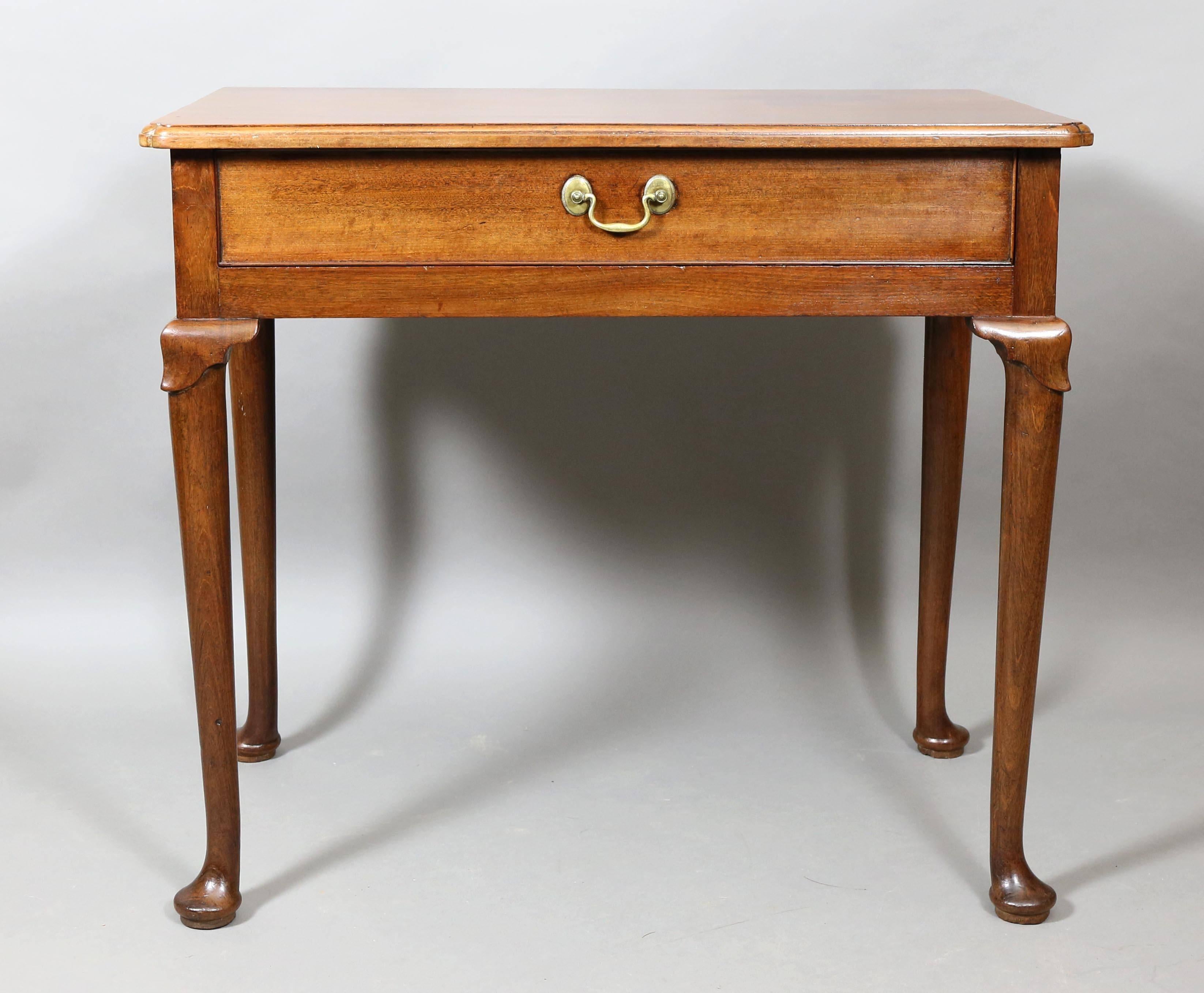 With rectangular top with molded edge over a single drawer raised on circular tapered legs headed by lambs tongue carving, pad feet.