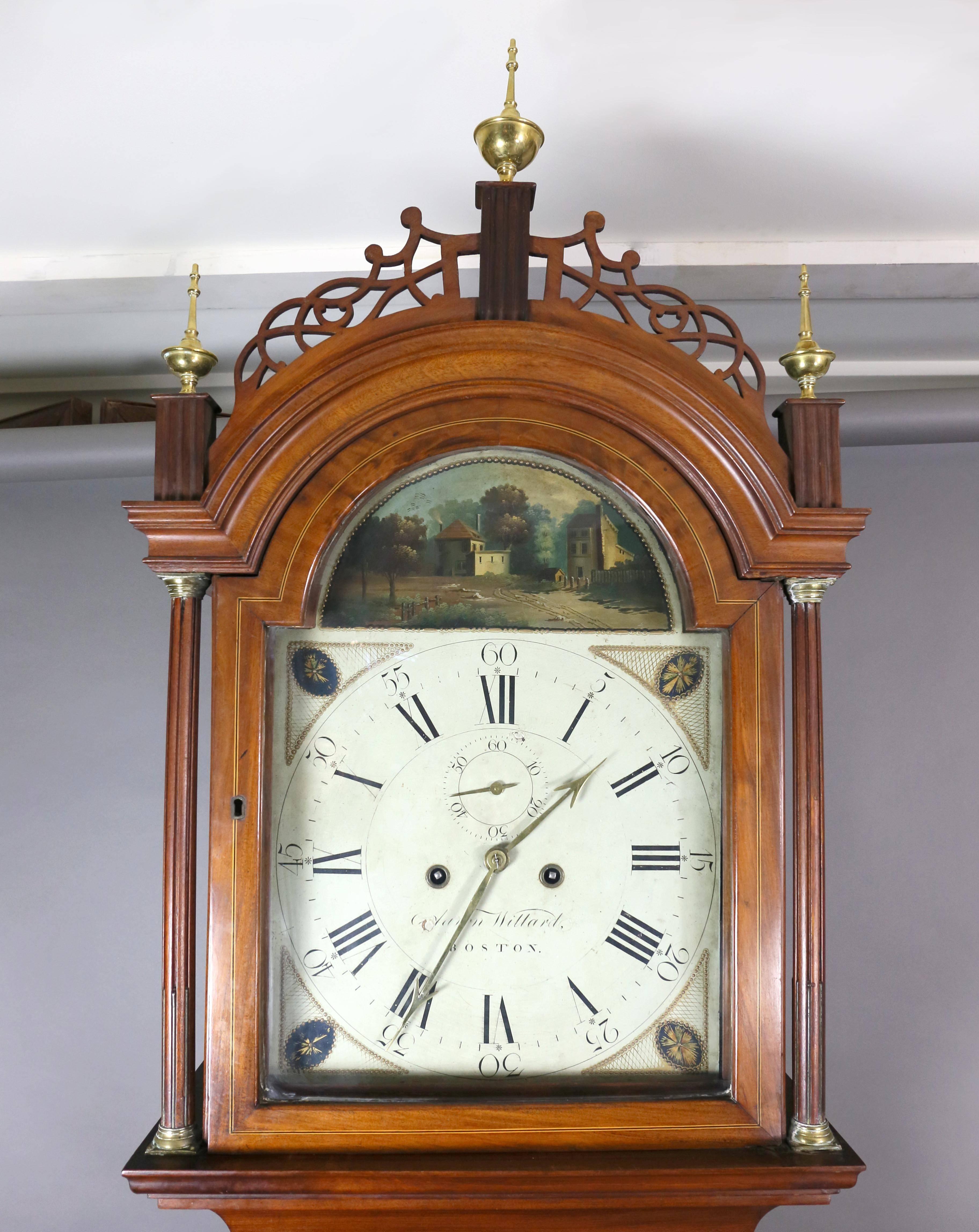 The bonnet with fretwork decoration and brass finials, the glazed door enclosing a dial with buildings in landscape arch and cream painted dial Signed Aaron Willard, Boston with oval painted paterae in spandrels, pendulum door flanked by