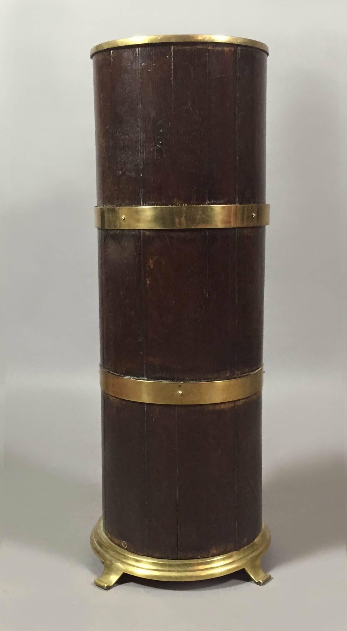 Cylindrical form with pieces of mahogany arranged vertically and two horizontal brass bands.