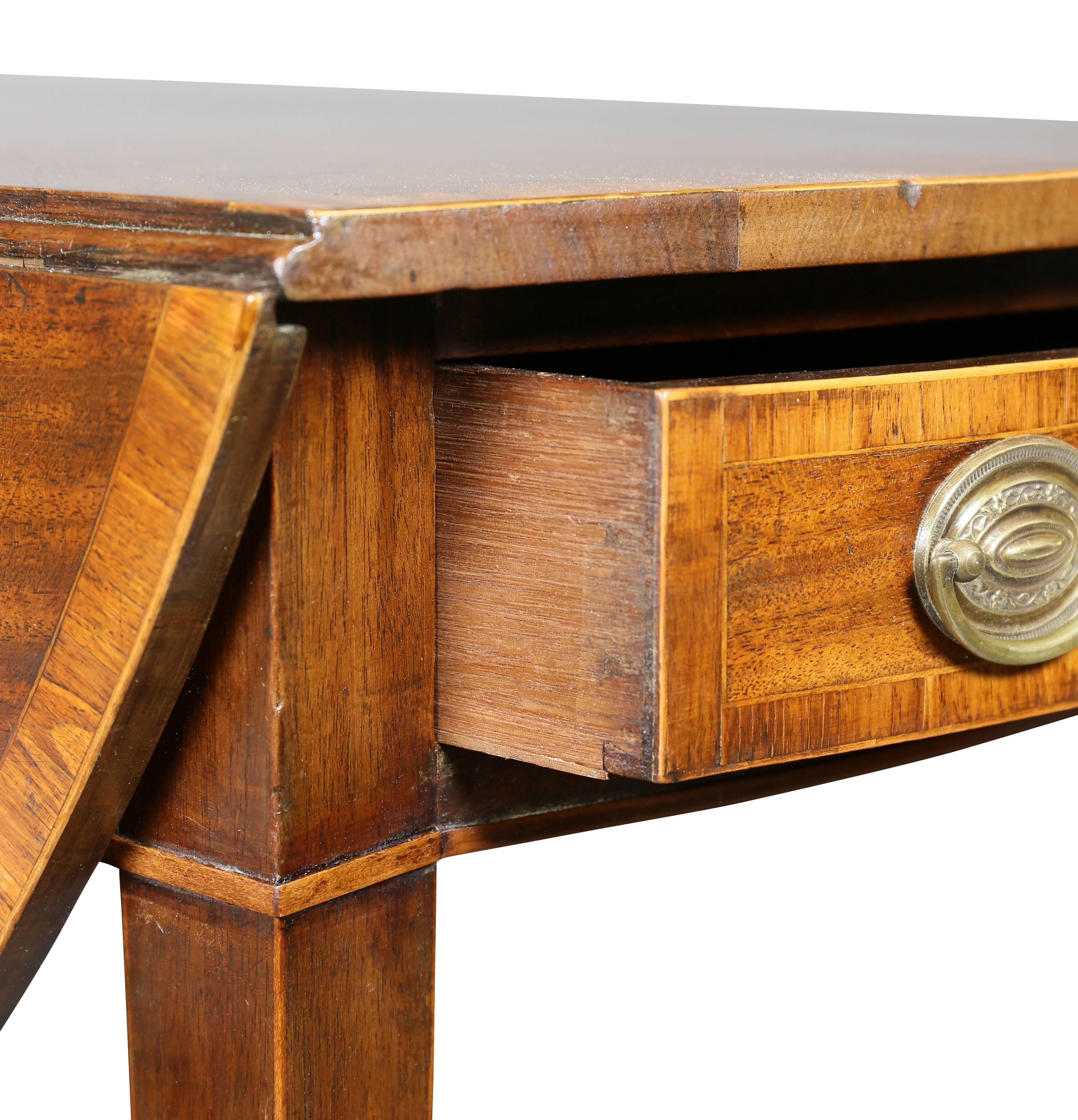 Bowed rectangular with D shaped leaves over a frieze containing a drawer and an opposing false drawer, square tapered legs and casters.