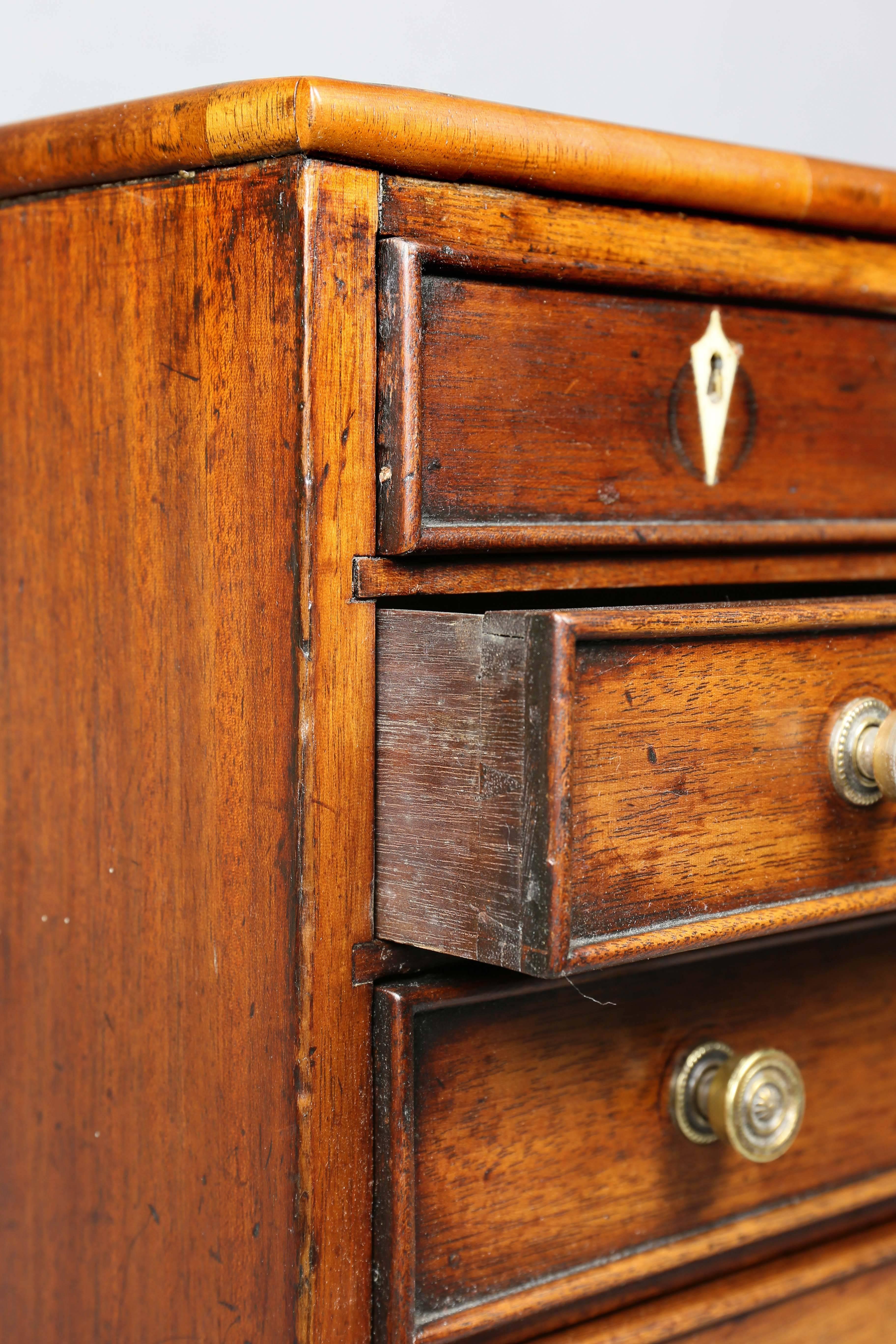 Rectangular top over four drawers, bracket feet. Brass knobs with inlaid escutcheons.