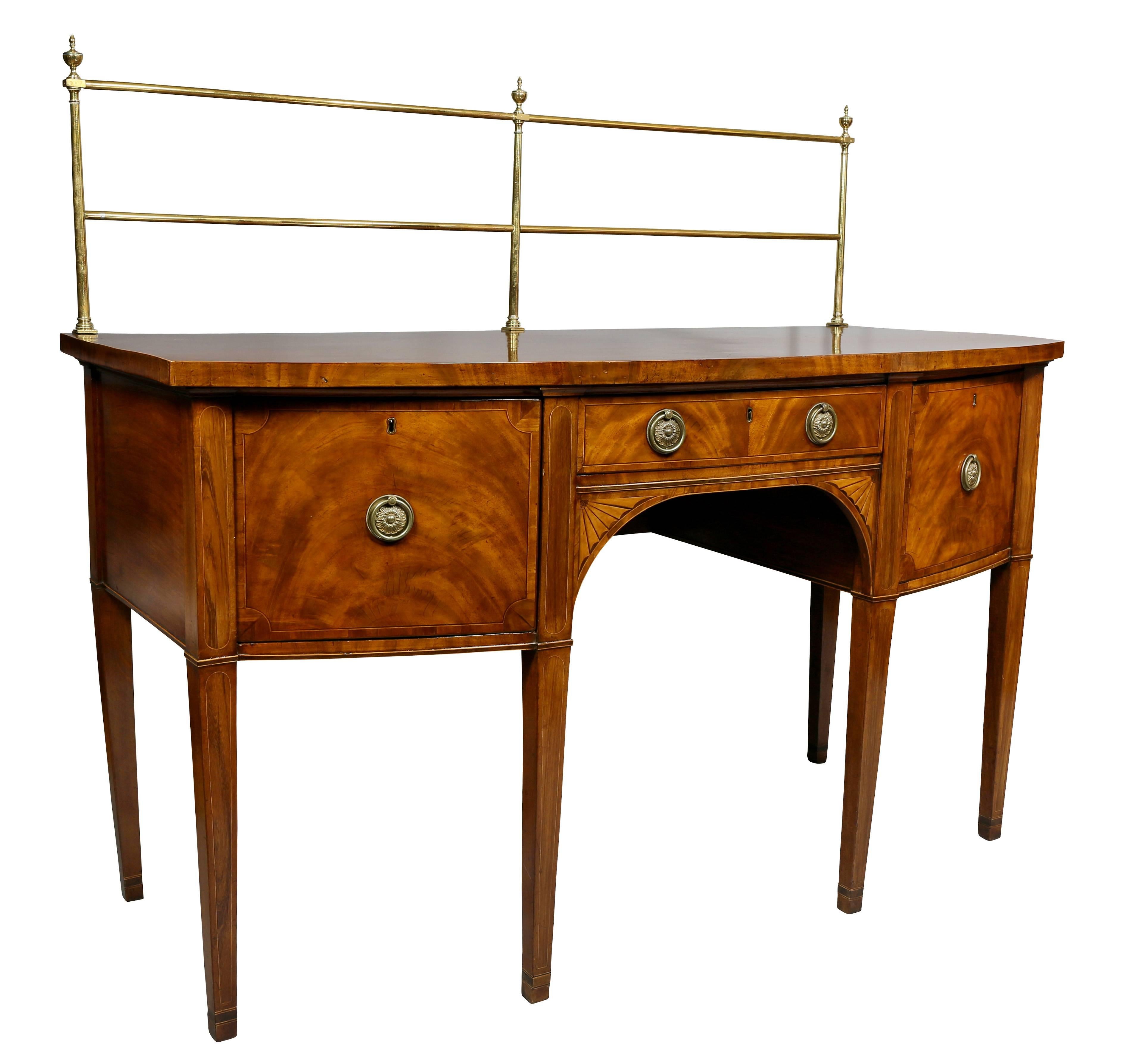 Sideboard with removable brass curtain rail over a bowed top with crossbanded edge, central drawer over fan inlaid spandrels flanked by two deep drawers, raised on square tapered legs.