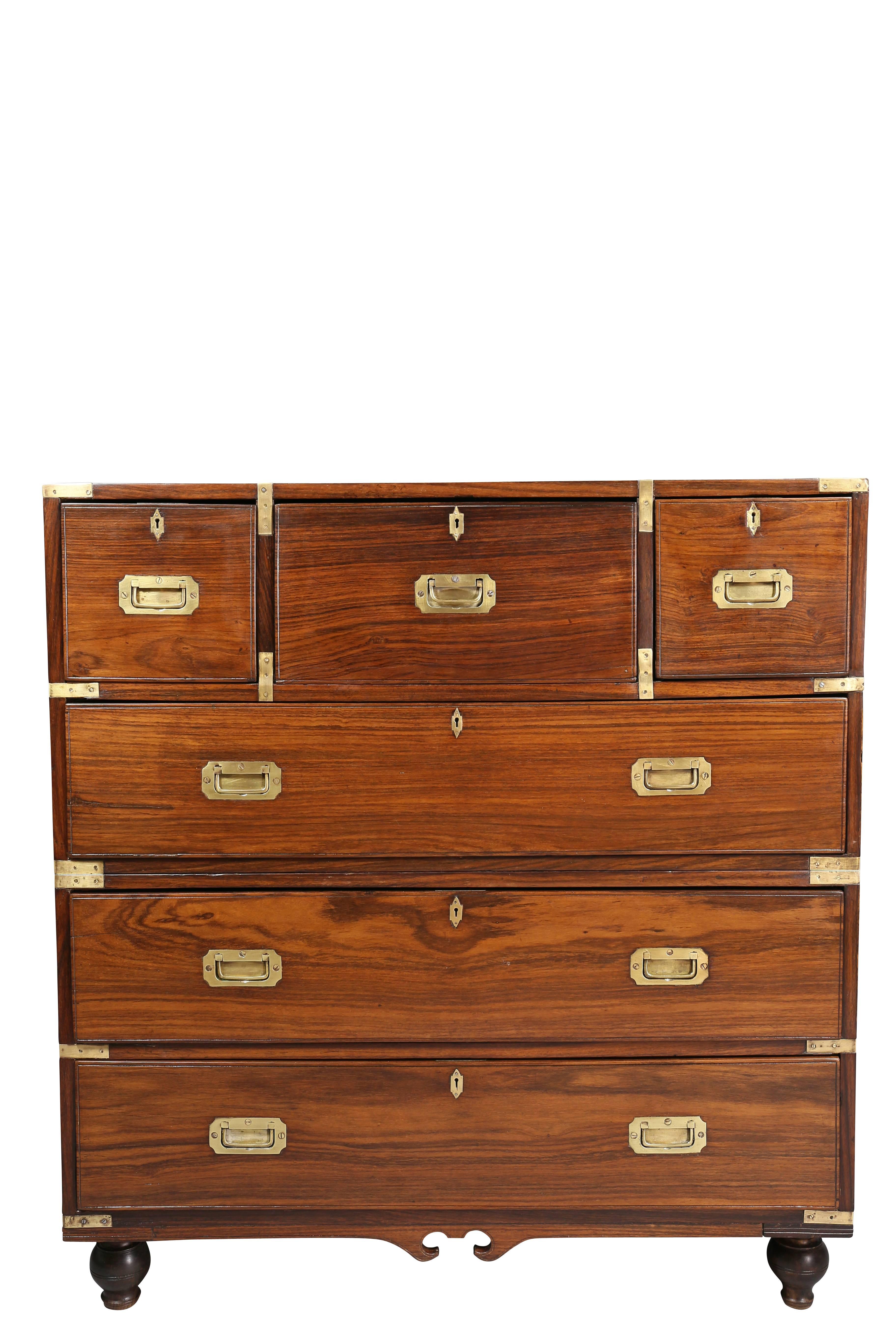 In two sections with rectangular top and brass-mounted corners over a central desk drawer flanked by two small drawers over three drawers with inset brass handles , apron with central reverse broken arch, toupie feet. Carrying handles on side of one