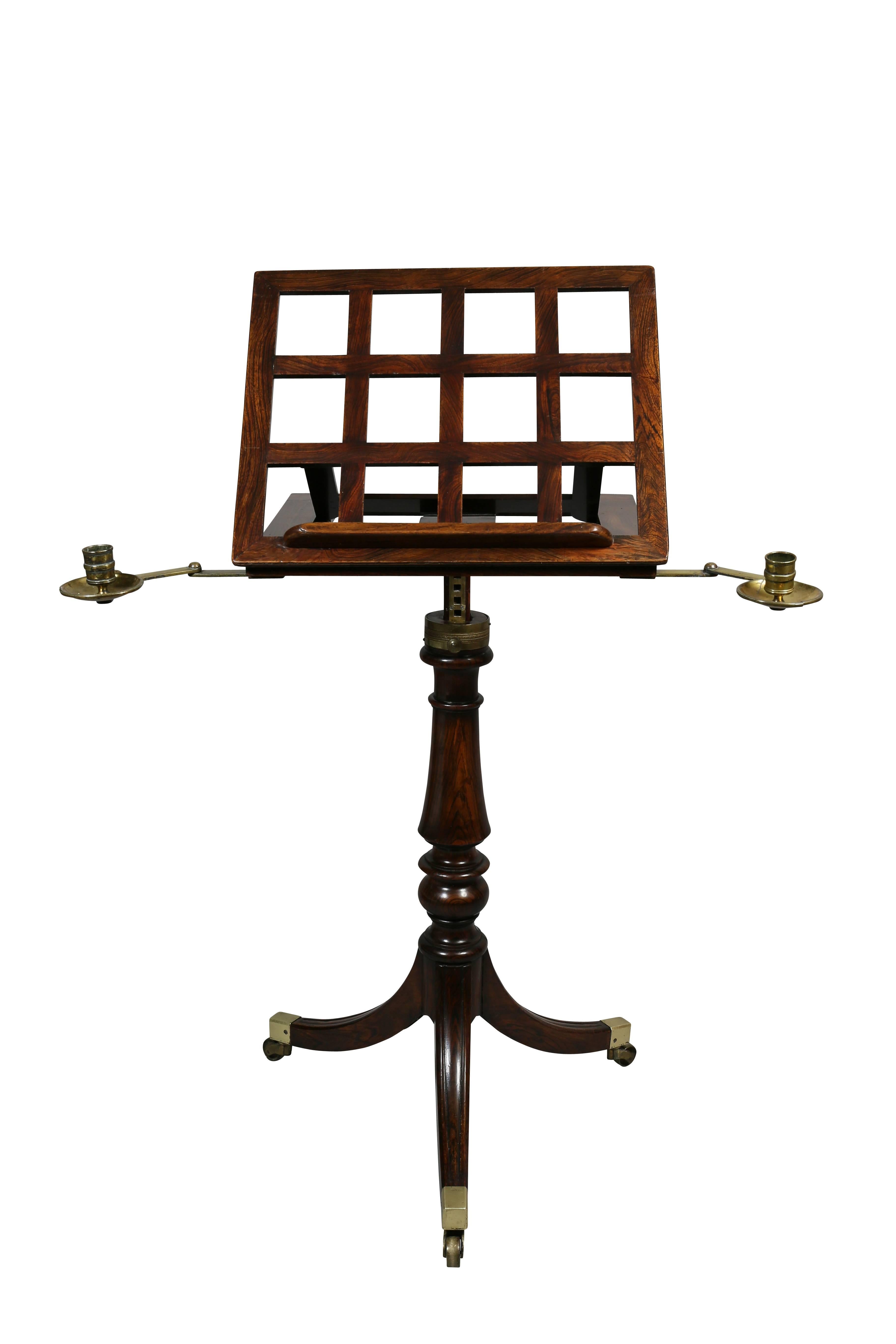 With tilting grill form adjustable book stand with original detachable brass candle arms, base with ratchet height adjuster turned support raised on tripartite base with casters. Caster cup signed BS&P Patent.