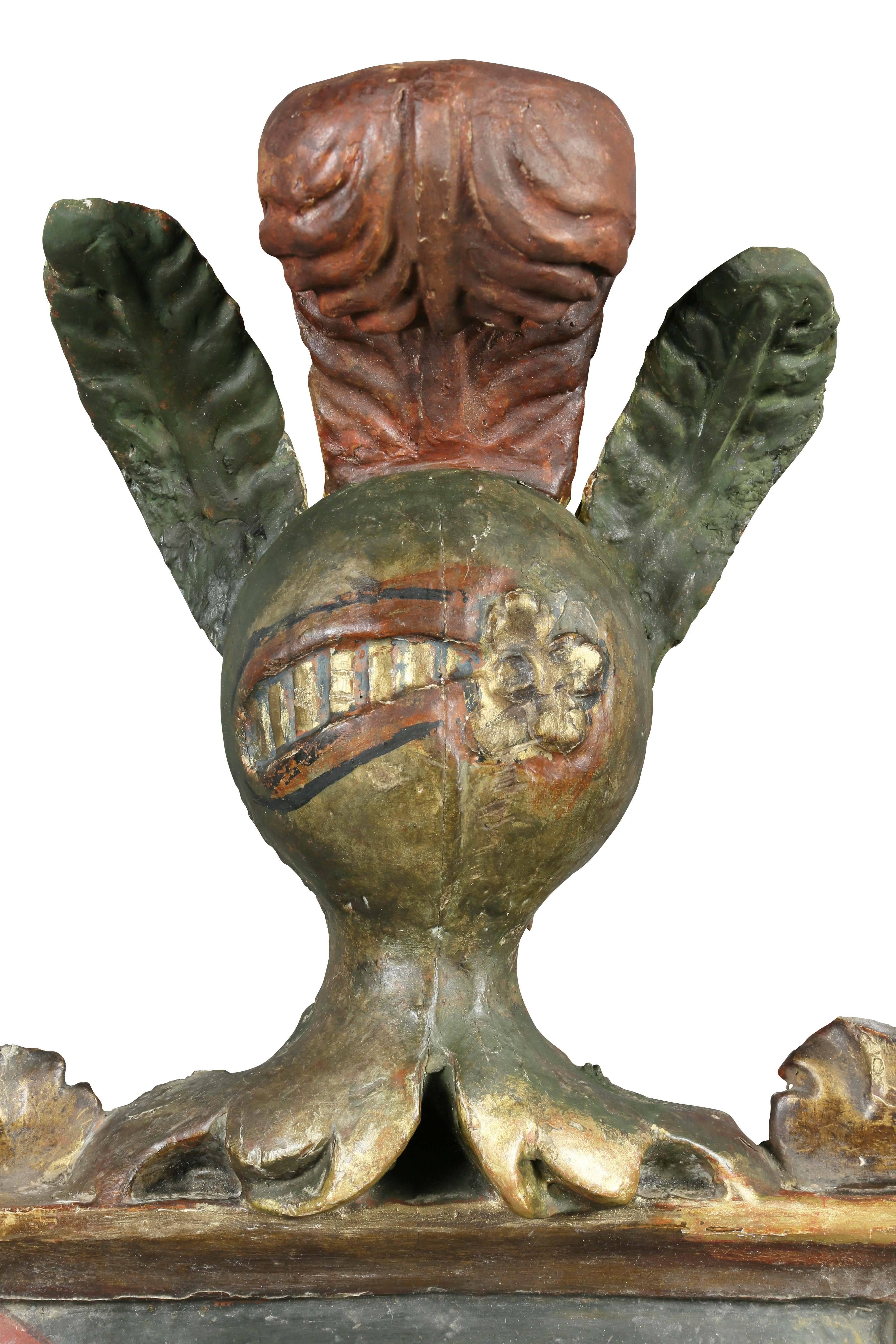 With a gladiator helmet with plume top over a shield flanked by shaped acanthus carved frame.