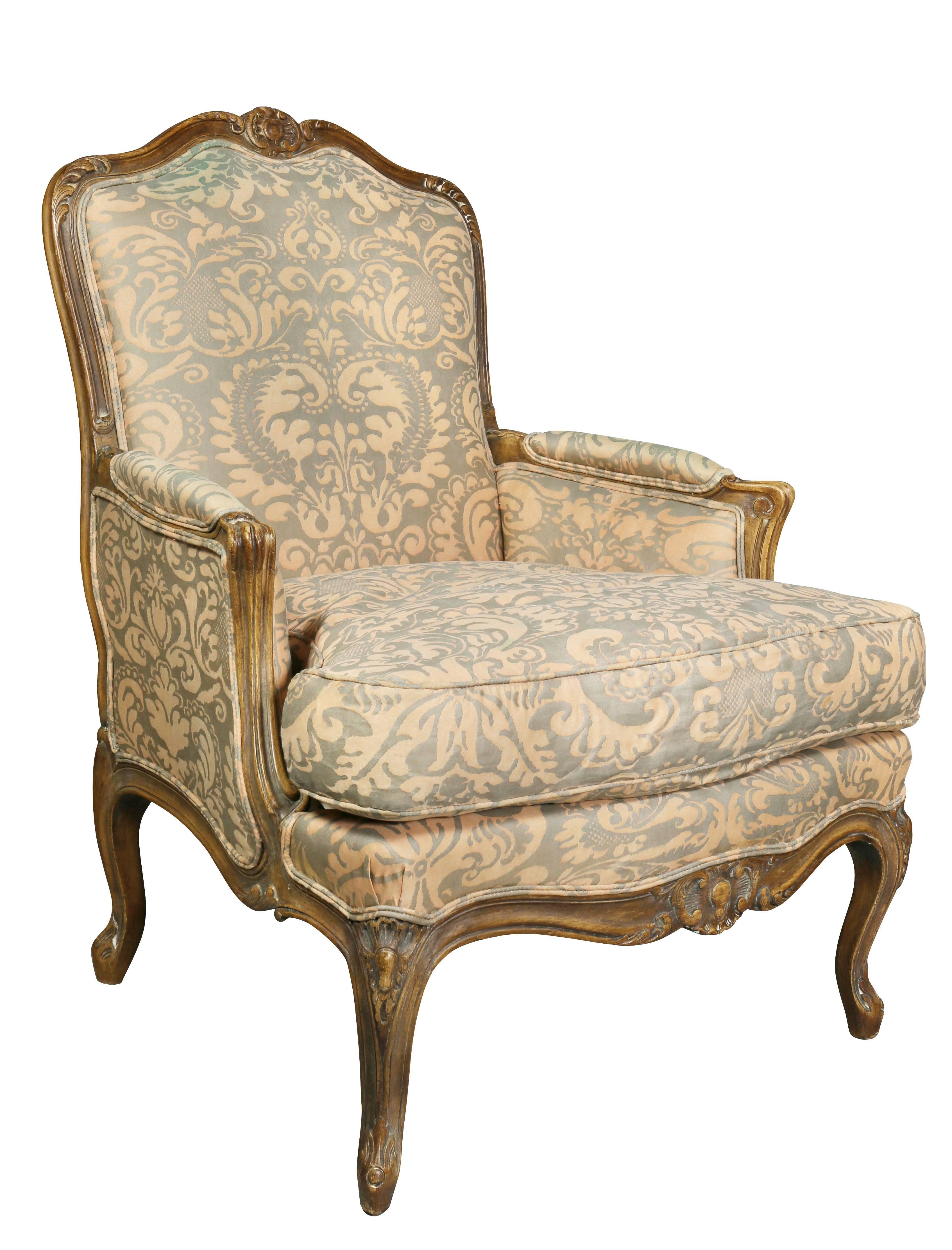 Each with a serpentine back within a carved frame and seat raised on cabriole legs, and upholstered in Fortuny fabric. Top of back of one chair with water bleed mark.
