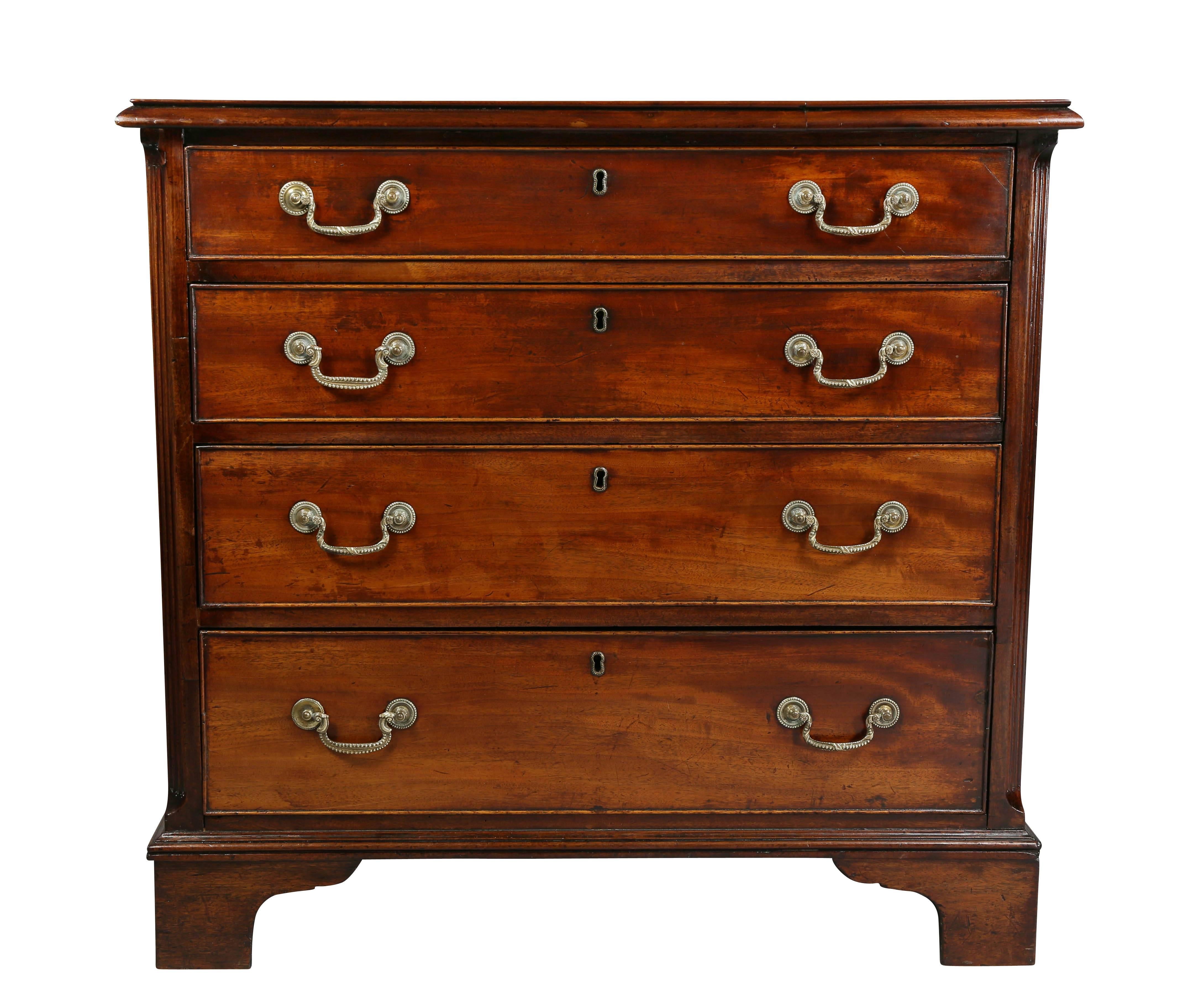 Rectangular top with crossbanding and inlay, molded edge raised on four graduated drawers flanked by chamfered fluted corners raised on bracket feet.