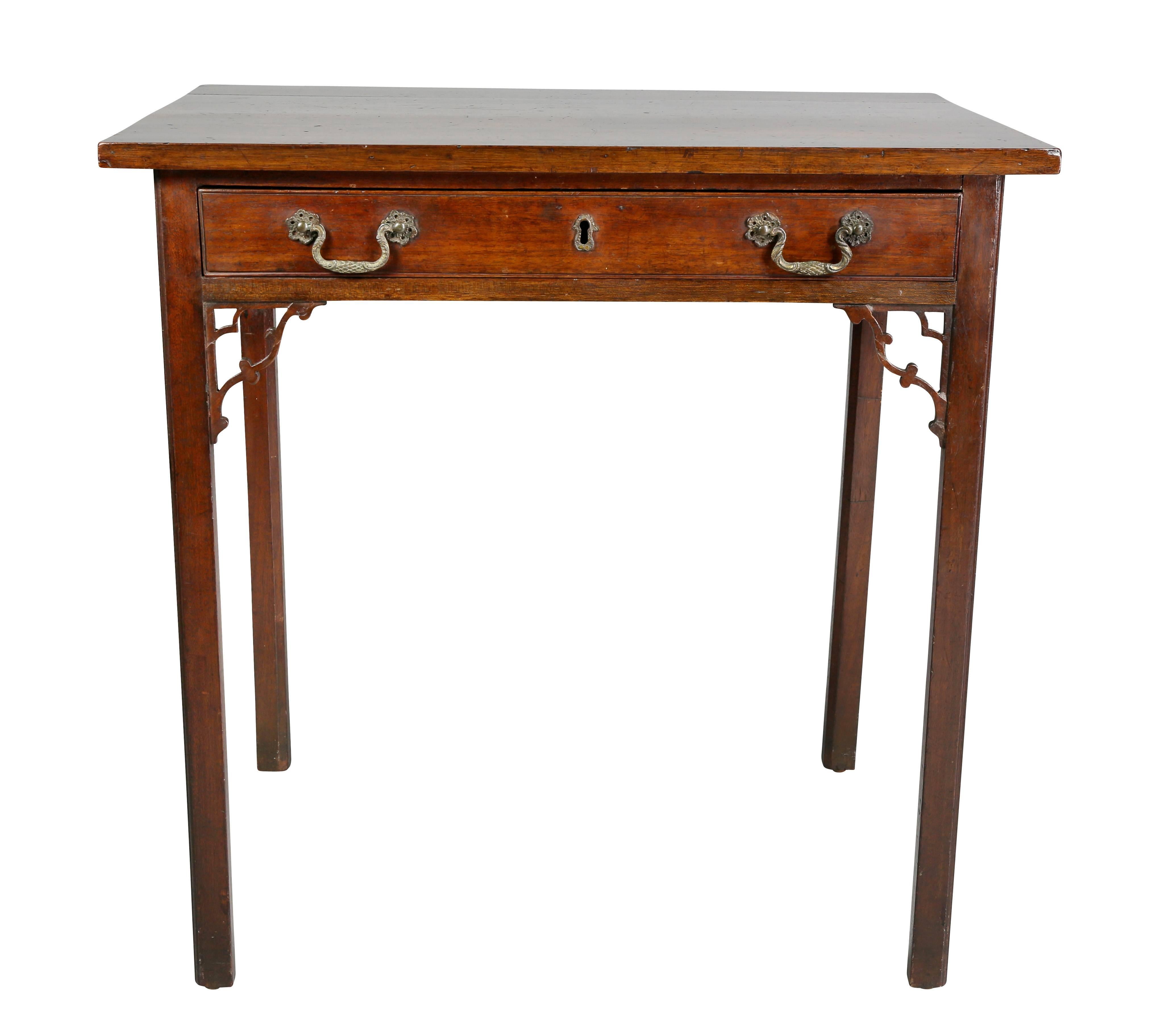With rectangular top over a single drawer with two handles raised on square legs with shaped spandrels.