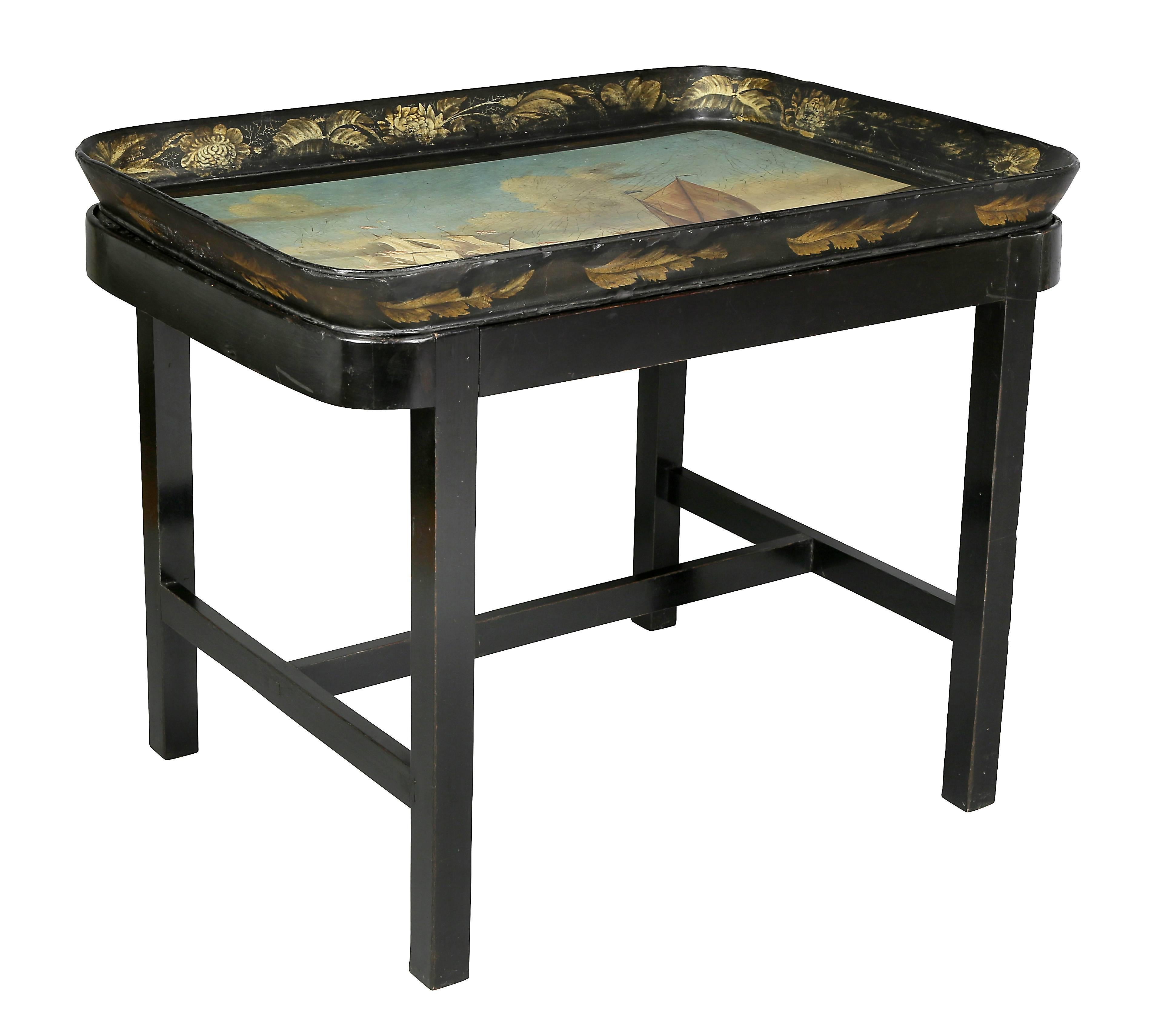 The tray with scene of ships at sea raised on an ebonized base with H form stretcher.
