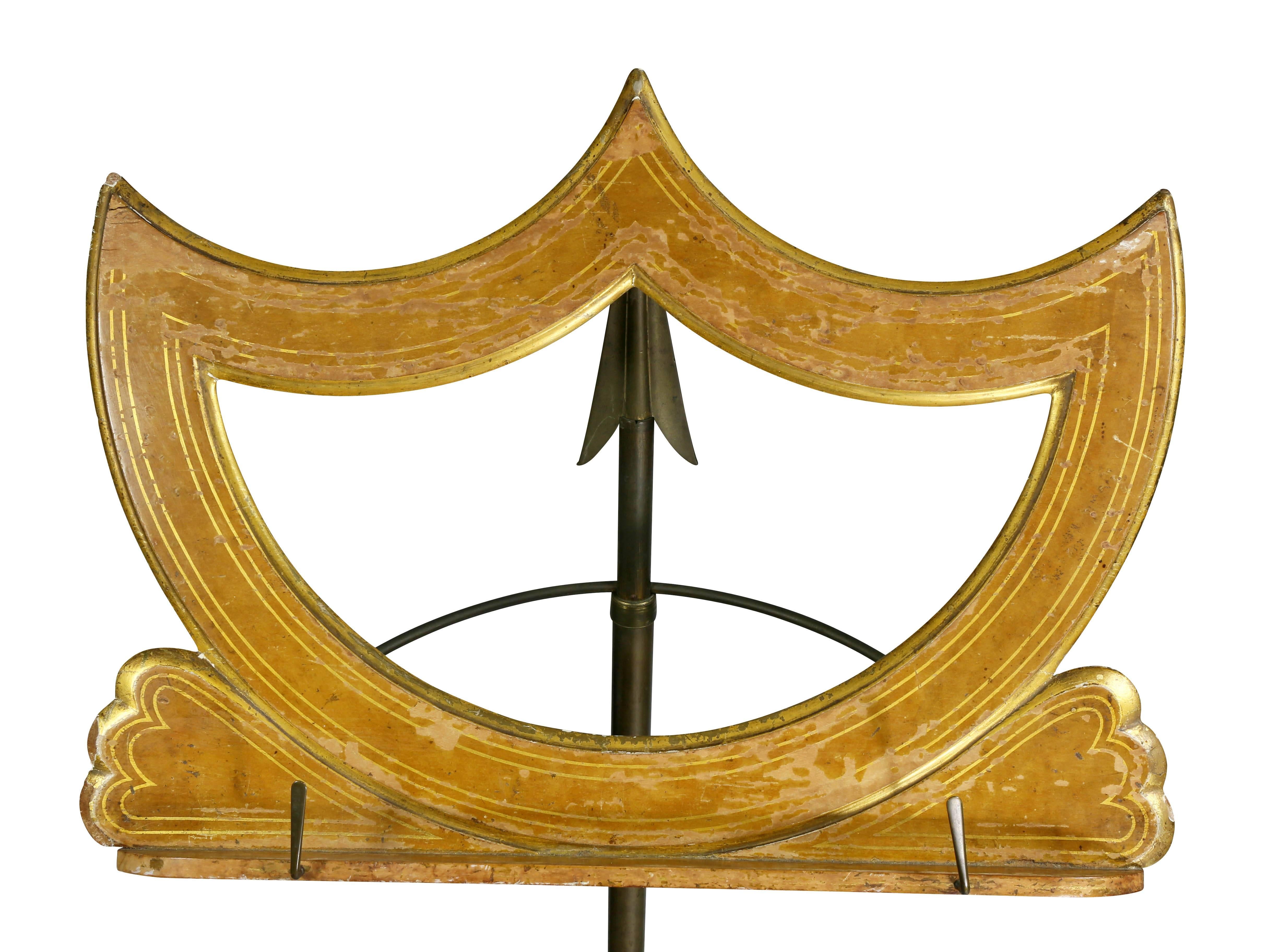 With triangular iron base and arrow form support, shield form book rest.