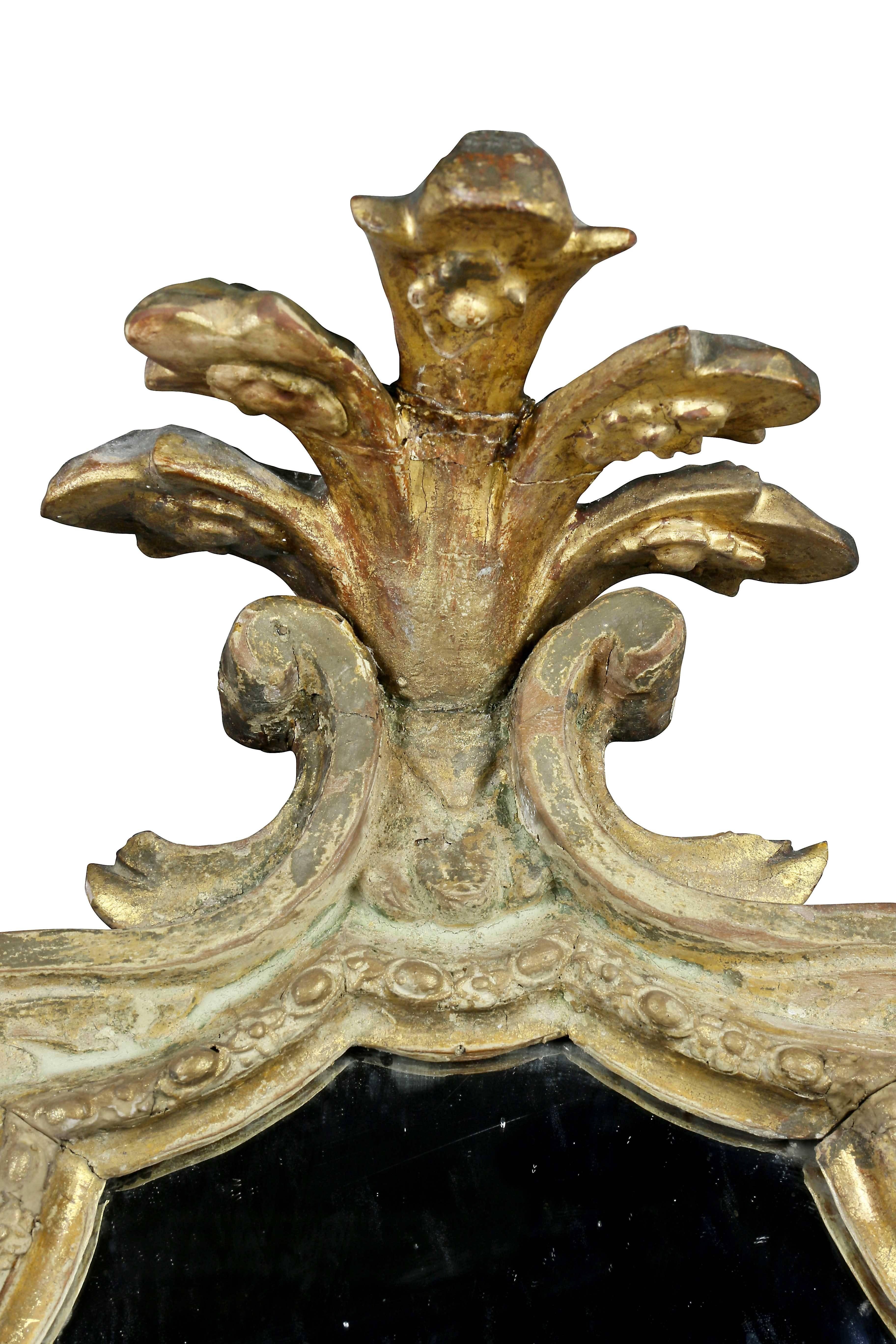 With five petal overhanging crest over a shaped carved frame with mirrored outer frame, satyre mask at base which once held a candle arm.