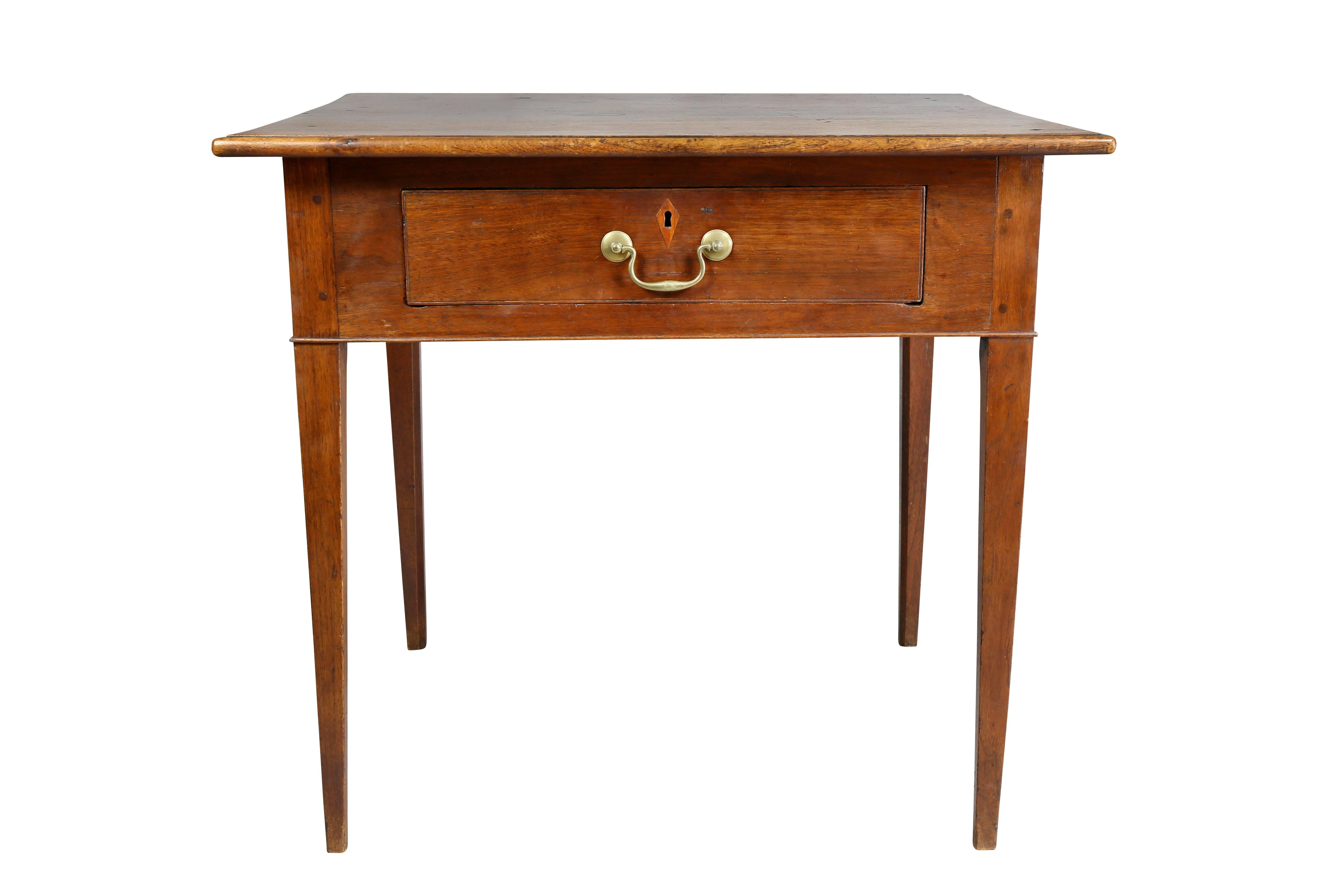 Rectangular top over a single drawer with inlaid escutcheon and original bail handle raised on square tapered legs.