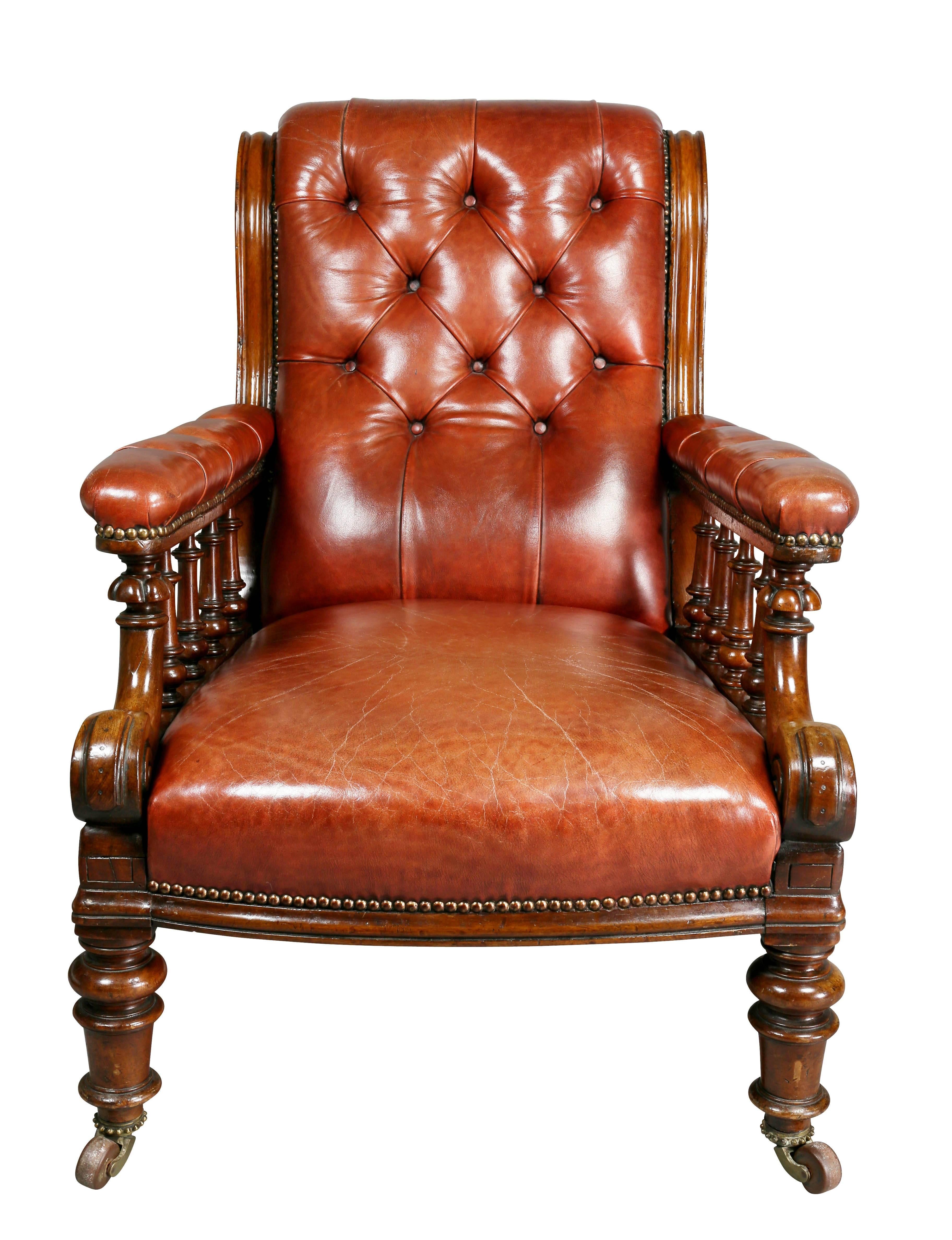 With buttoned brown leather back and seat, arms covered with leather over spindles, raised on turned tapered legs with casters.