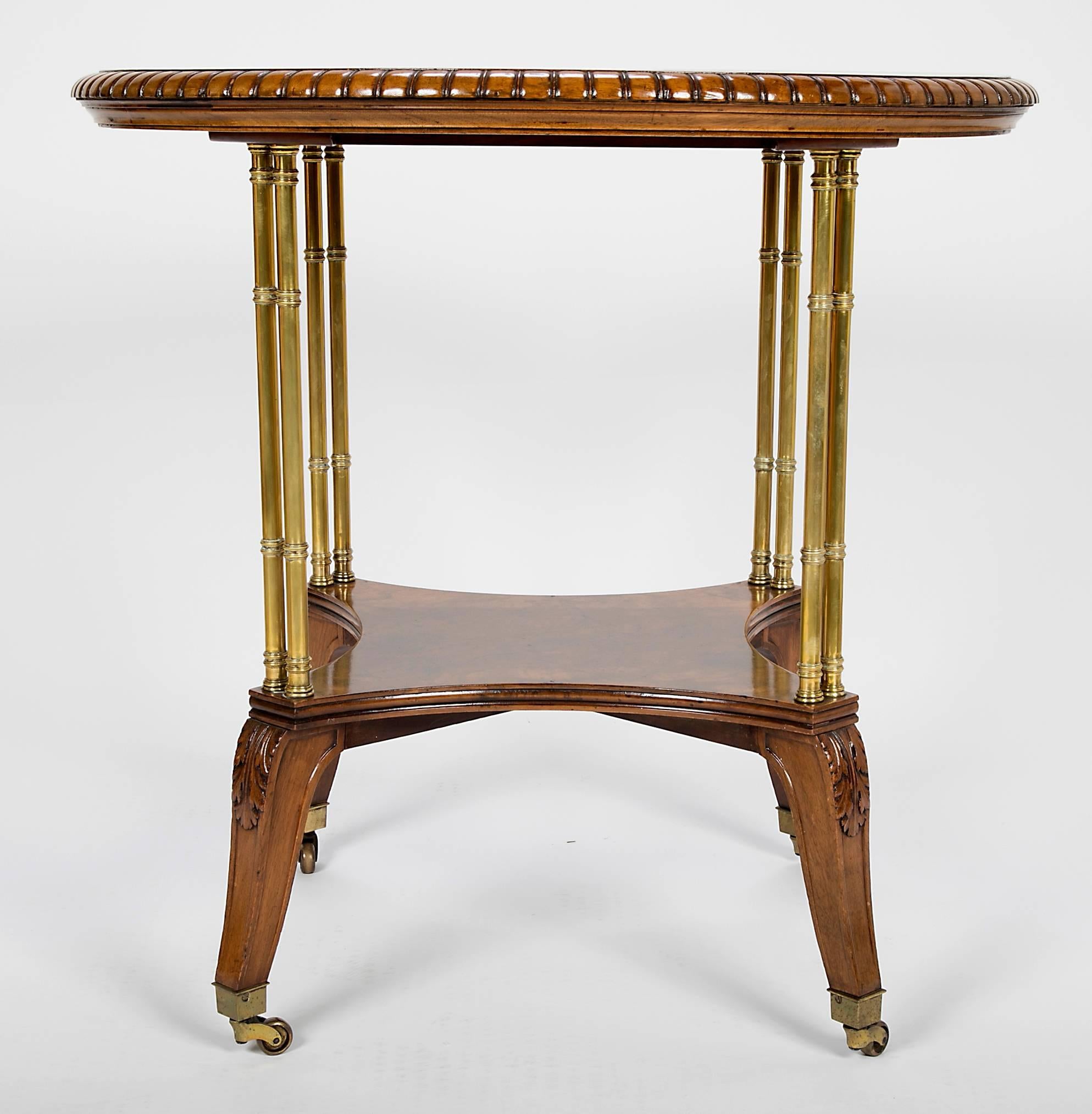 In the Regency style with circular burl top with carved beaded edge raised on bamboo turned brass supports, lower shelf and carved saber legs with brass casters. Stamped on underside of top. Holland & Co was granted a Royal Warrant Of Appointment