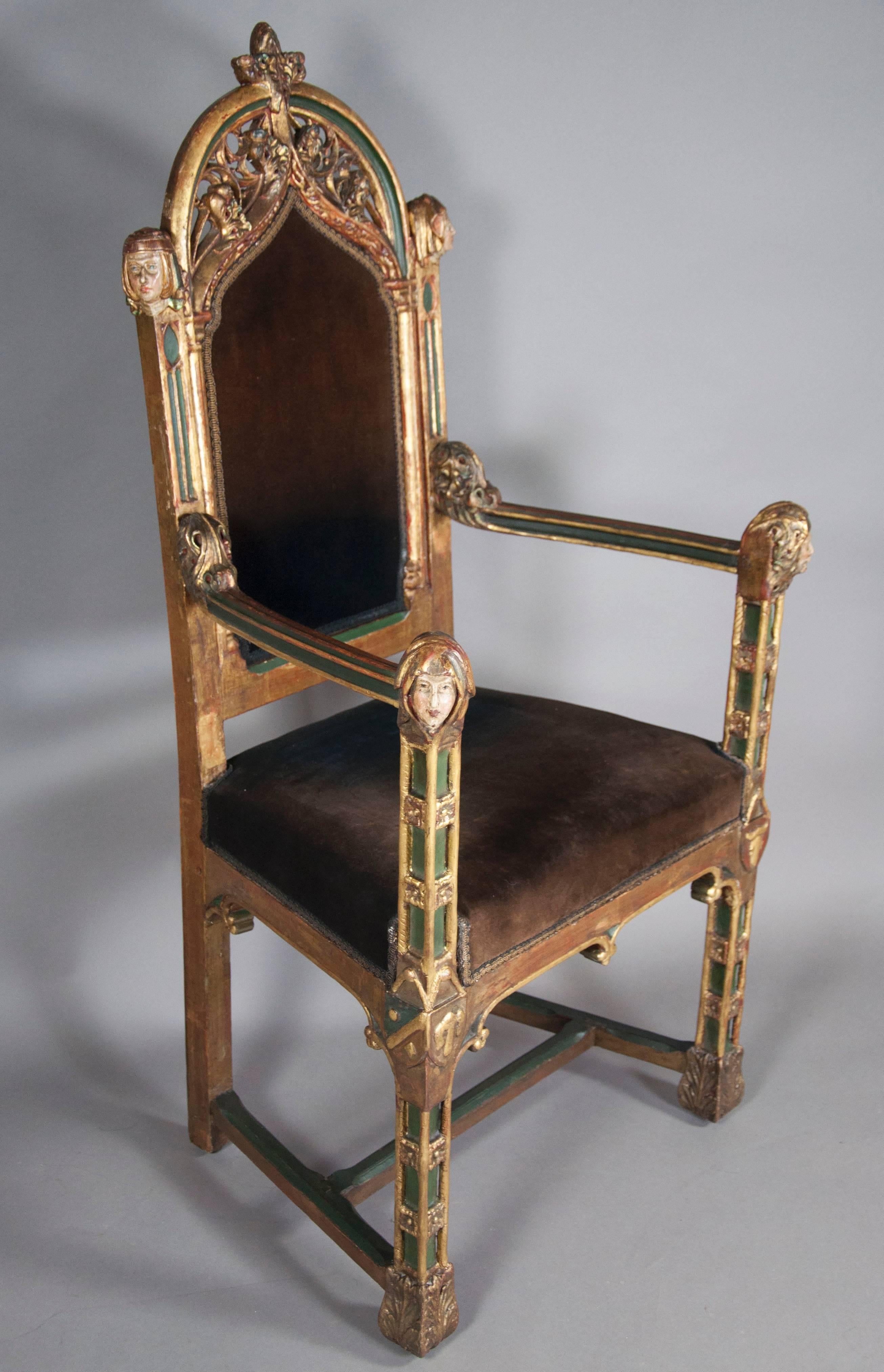 Gothic trefoil back with carved heads on either side of the back and at the end of the arms, velvet upholstered back and seat raised on square carved legs and H-stretcher.