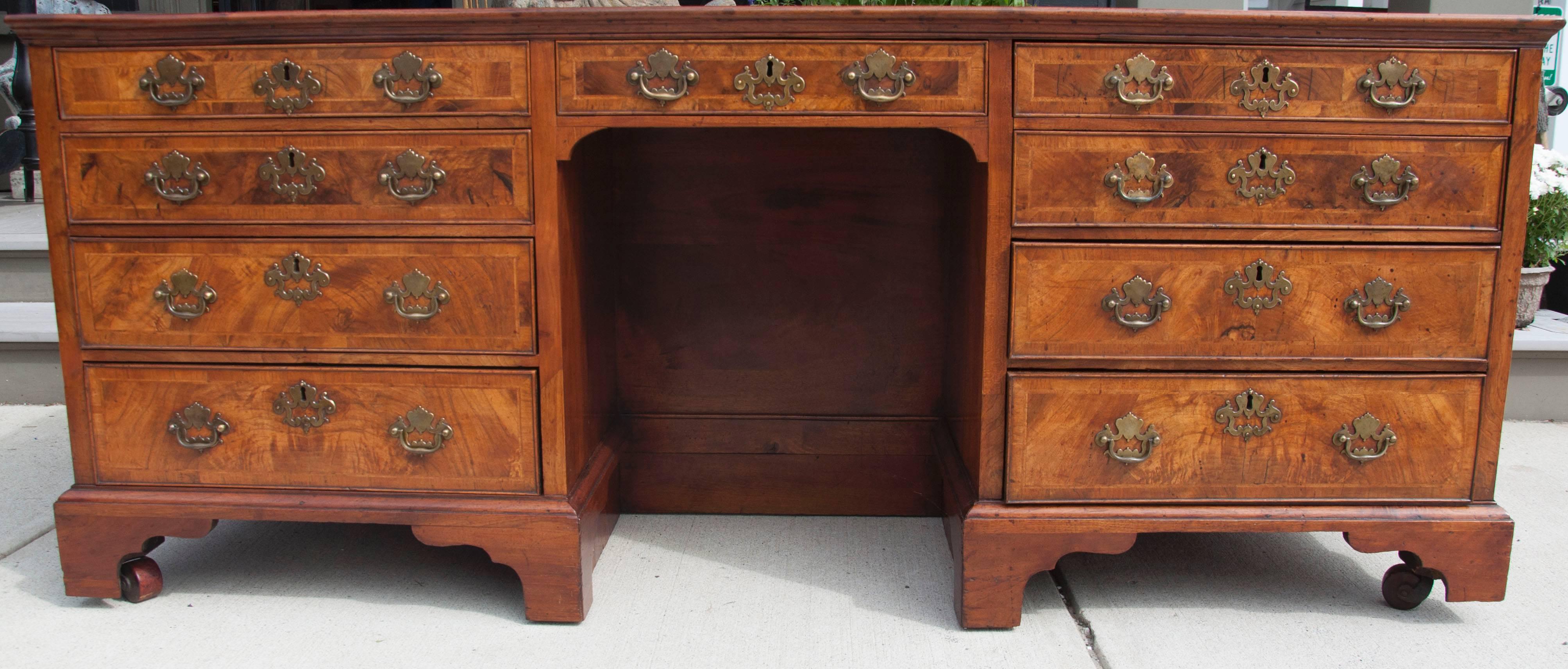 Rectangular brand new inset dark olive gilt tooled leather top with moulded edge over a centre niche with a drawer above and flanking drawers over six drawers some false front to enable longer drawers on other side, carved panelled sides with brass