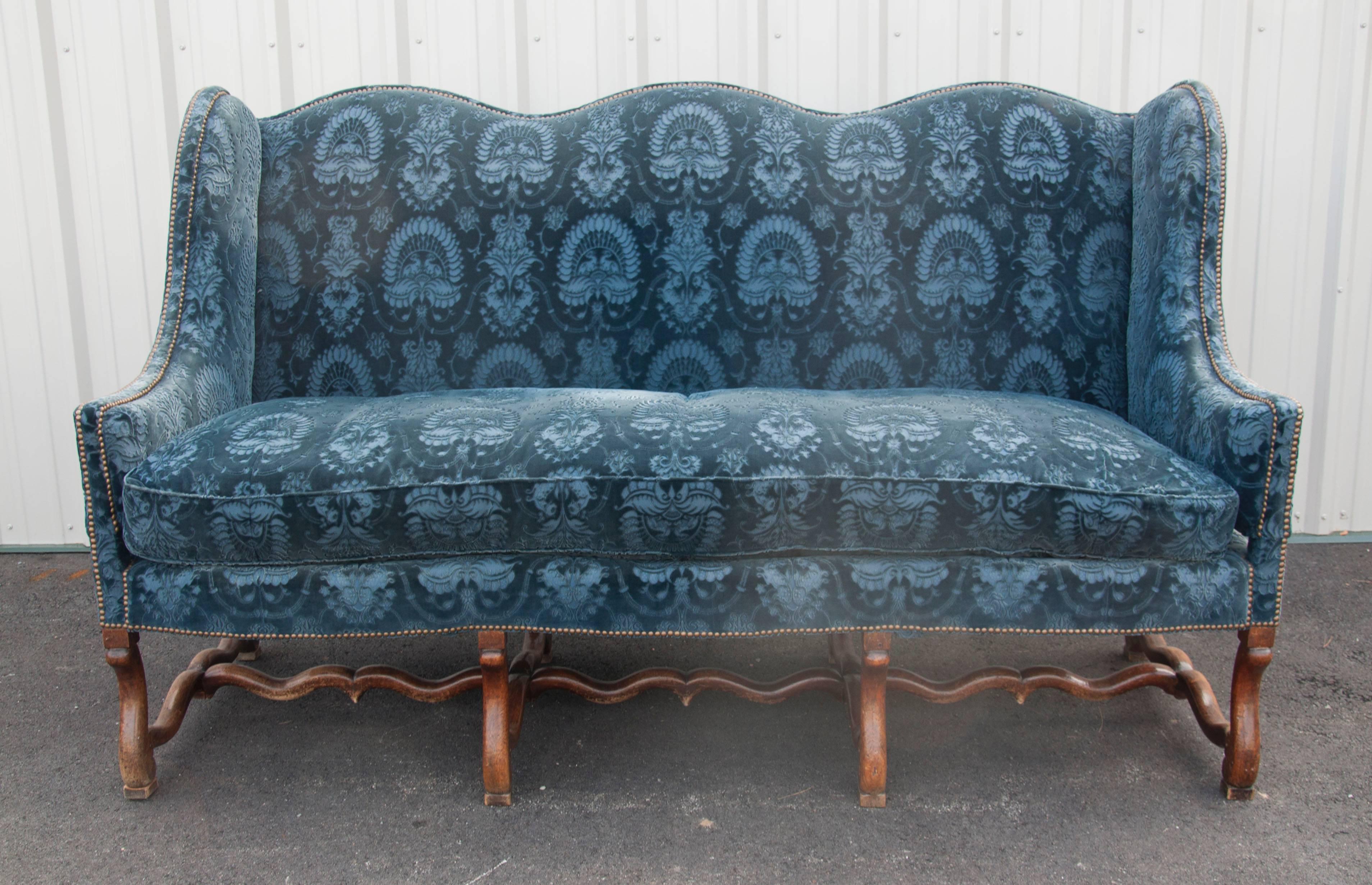 Extremely generous proportions with serpentine back and conforming seat with down filled cushion , S curved legs joined by stretchers. Upholstered in rich blue cut velvet with brass tacks. From Dallas Texas estate.