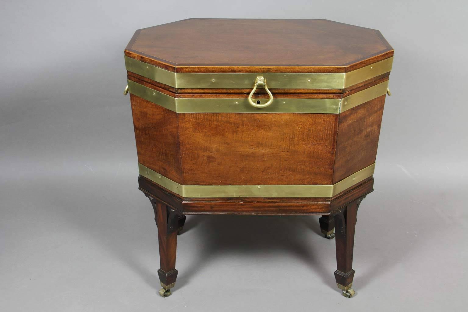 Elongated octagonal hinged lid opening to a fitted leaded interior with conforming case , the seperate base with square tapered legs with pierced spandrels , block feet and casters
