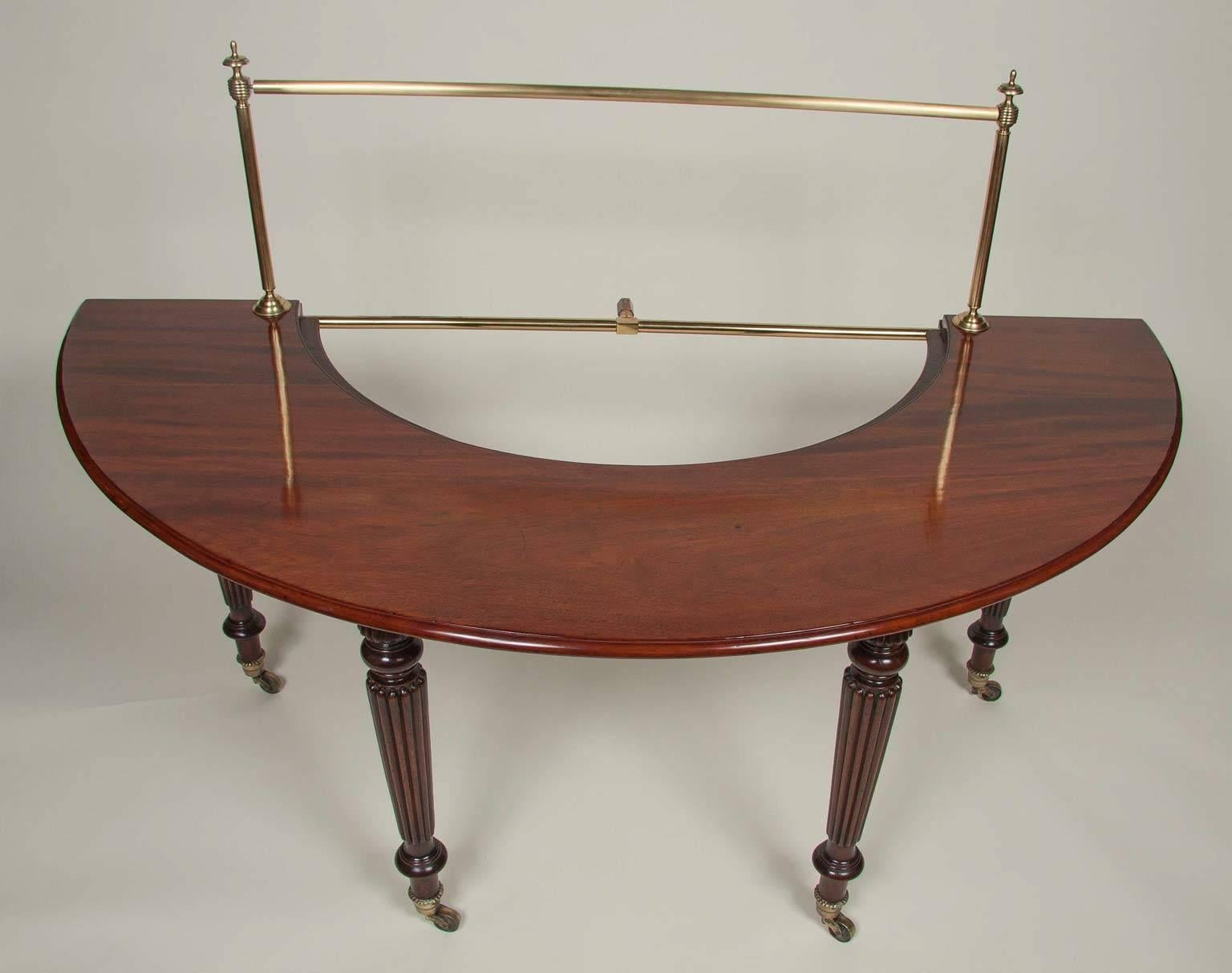 With brass curtain rail joining a demilune form top with removable inner section and rear hinged drop leaves raised on tapered circular reeded legs ending on brass casters. Most likely by Gillows. Note: These tables are used as side tables and also