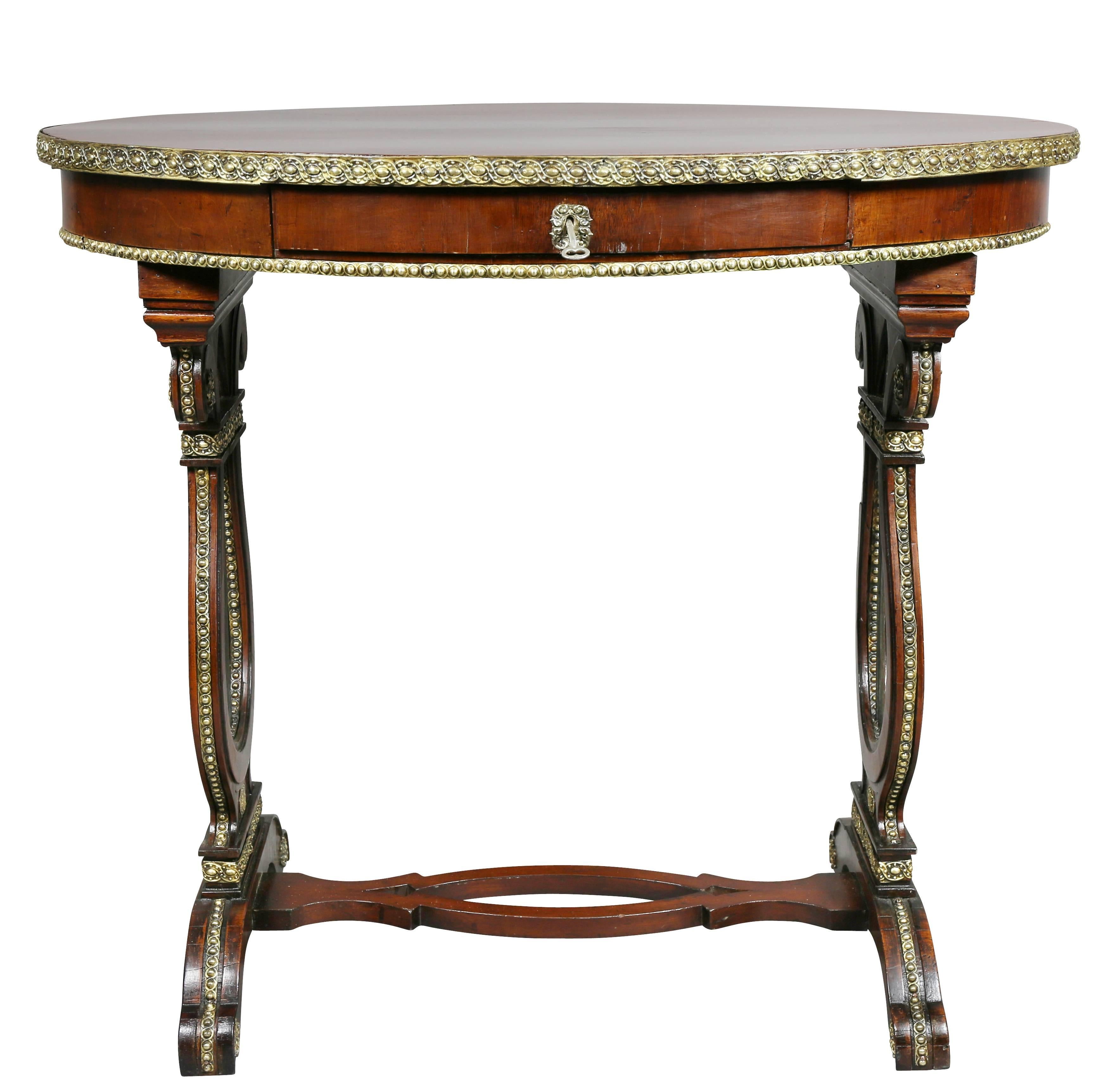 Oval top with pressed brass edge over a frieze with a drawer raised on trestle lyre form legs, pierced oval stretcher and scroll feet. Provenance; Belosselsky-Belozersky.