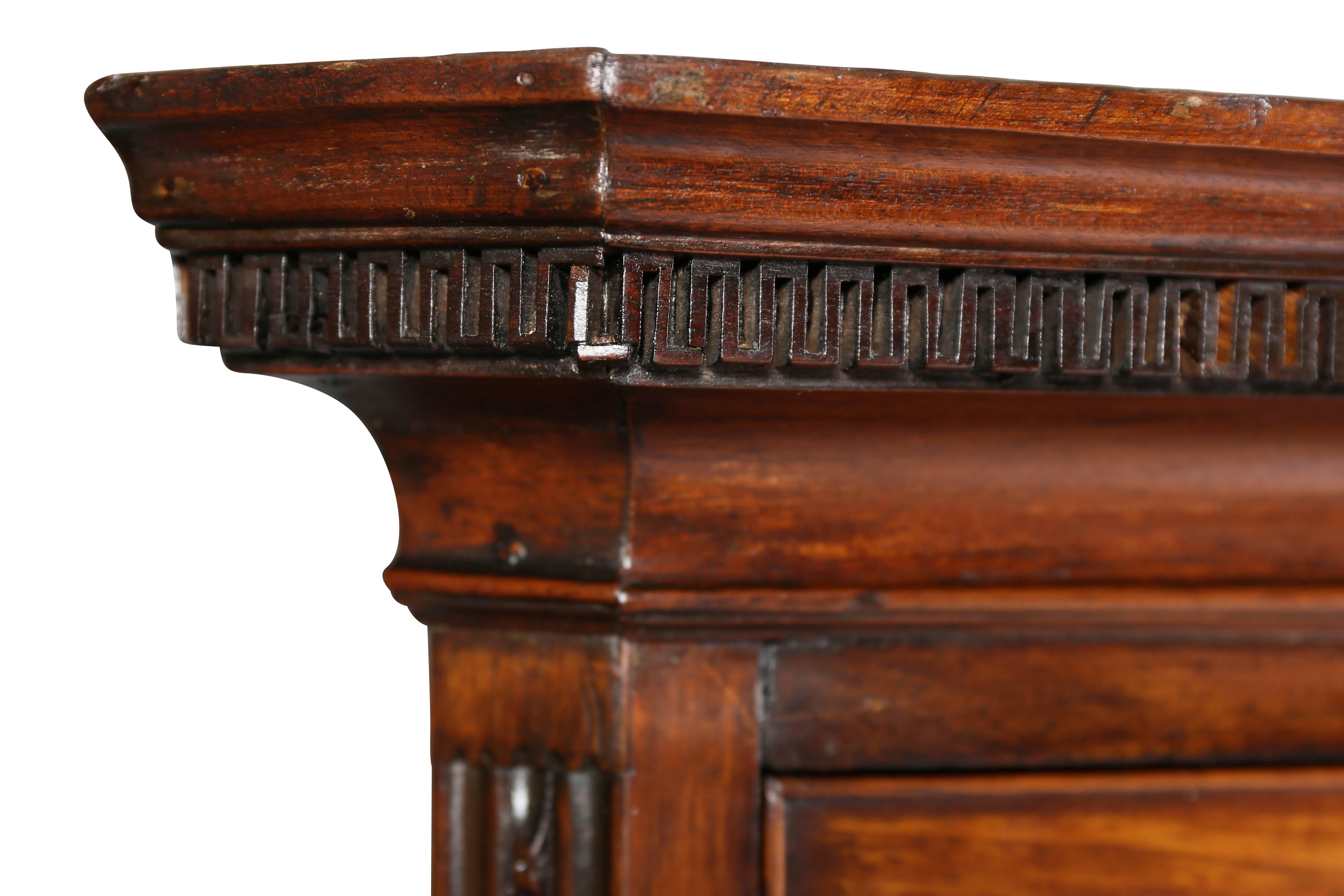Con cornice rettangolare con intaglio a chiave greca sopra due cassetti corti e tre lunghi fiancheggiati da intagli, la base con tre cassetti lunghi con lati intagliati in modo identico sollevati su piedi a staffa ogei.