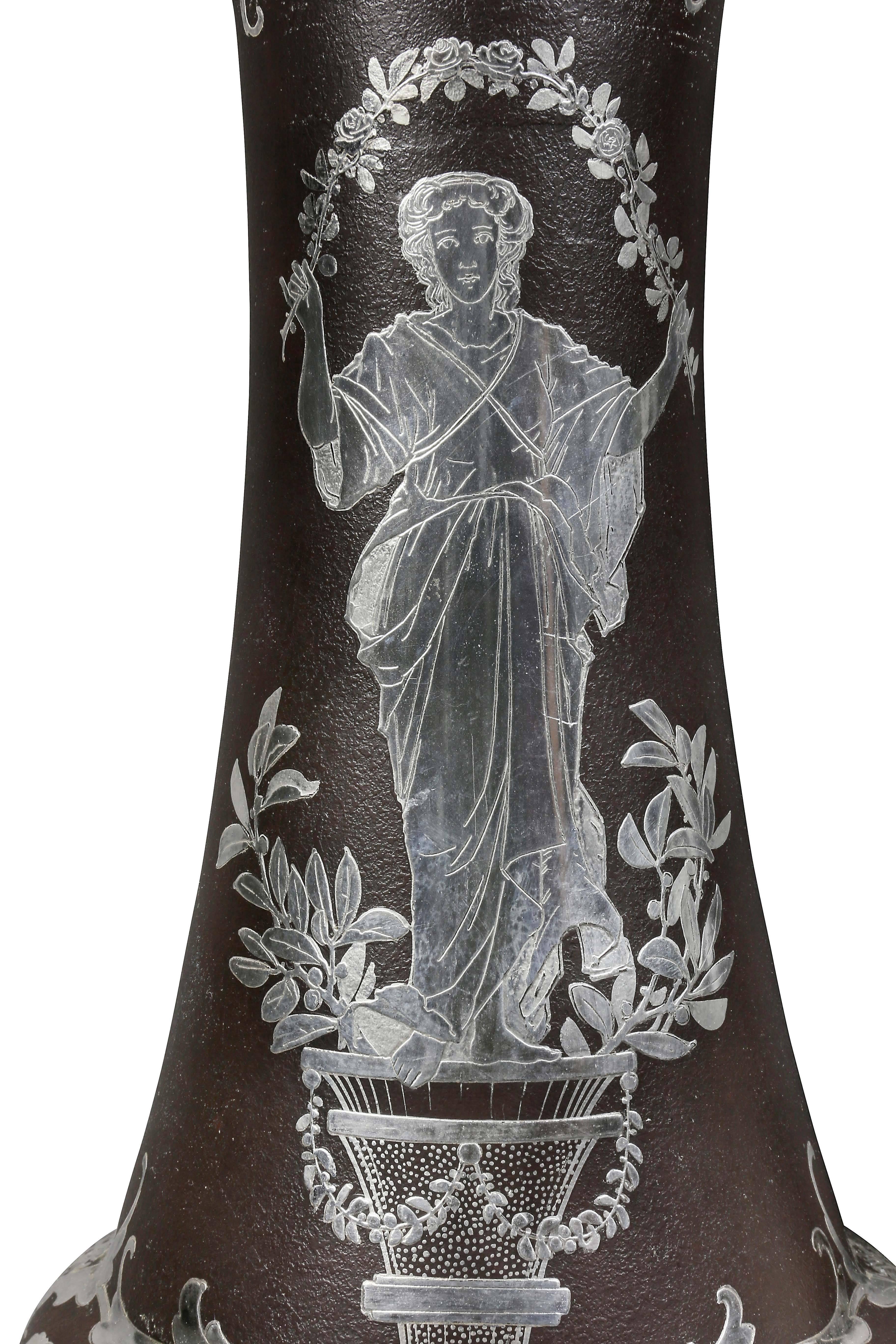 Flared cylindrical form decorated with a figure holding a wreath.