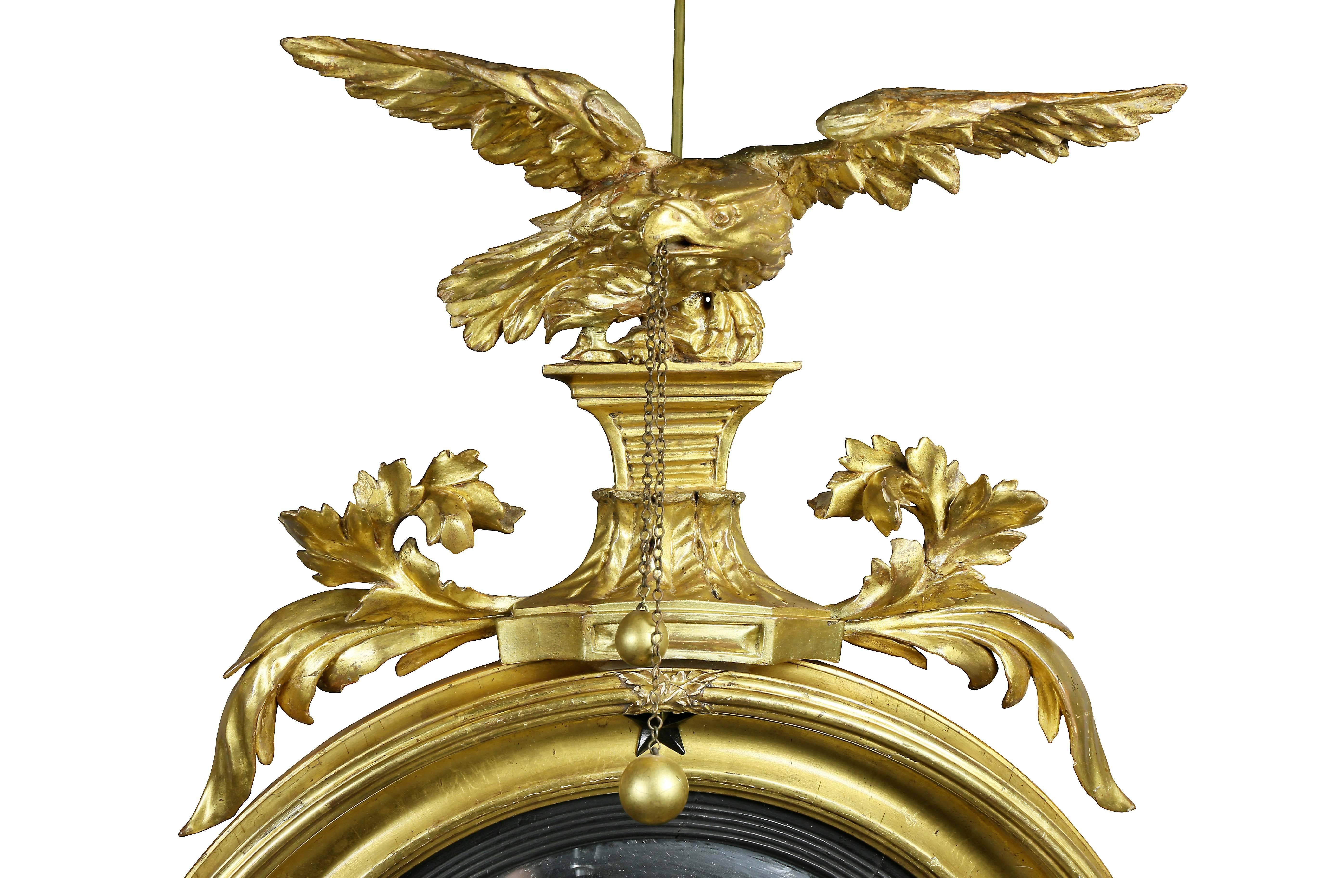 With eagle surmount over a convex plate and ebonized outer ring, the cove molded frame with Ebonized stars, two candle arms formed as finely detailed serpents.