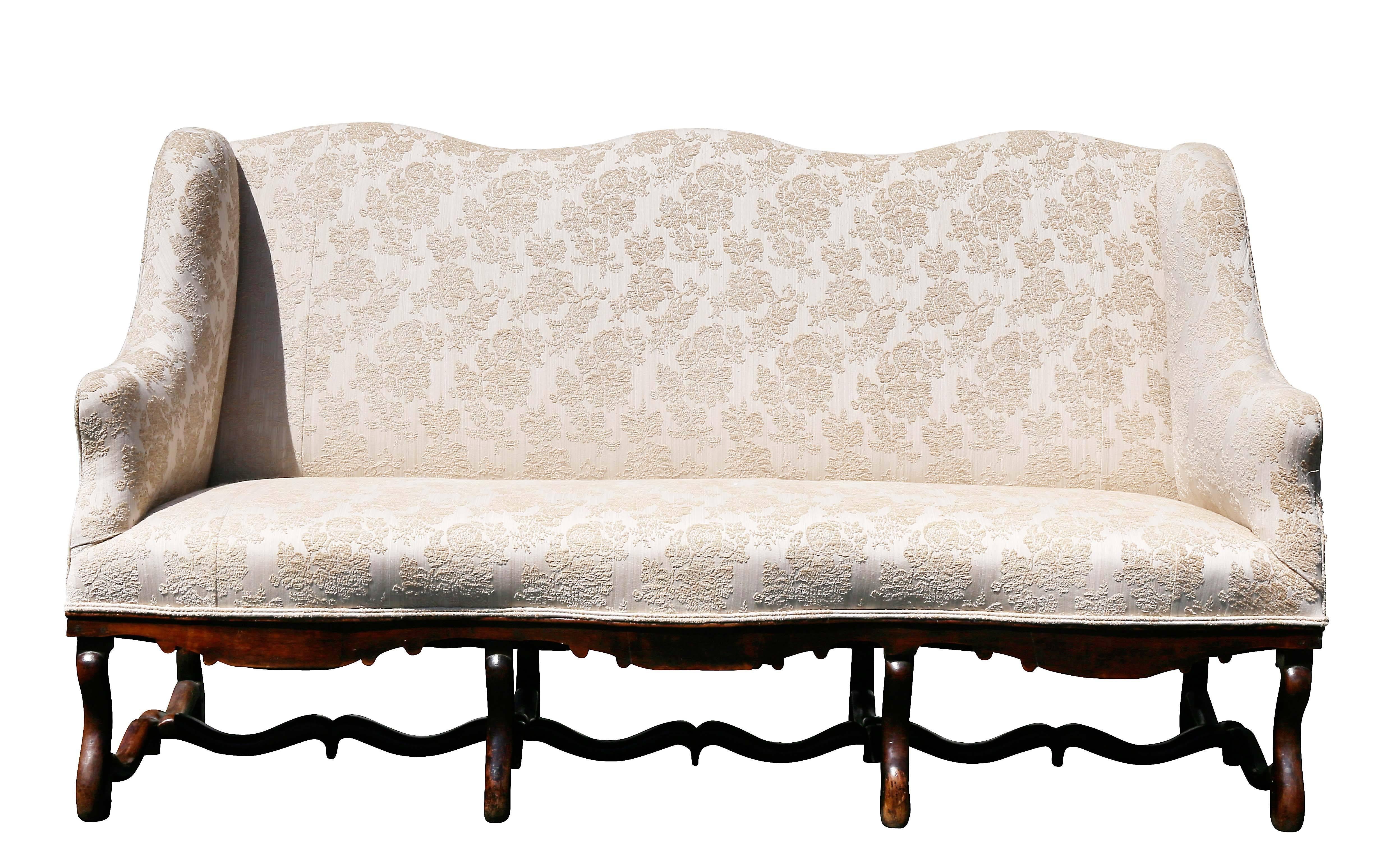 With serpentine shaped high back and conforming sides and seat, shaped seat rail, raised on curved legs joined by curved stretchers and scrolled feet. Os De Mouton form.