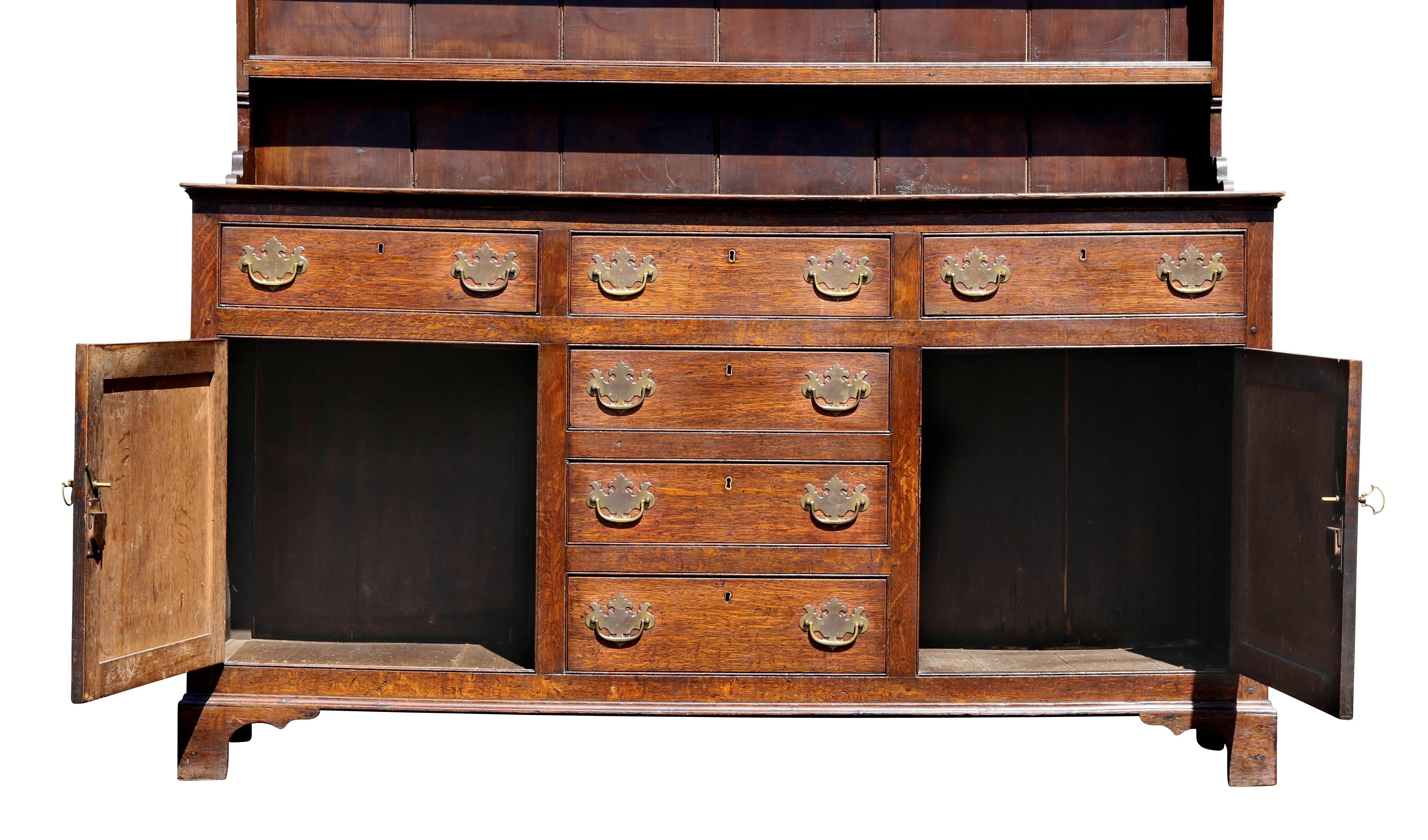 With molded dentilled cornice over three shelves, the base section with four central drawers flanked by a drawer and cabinet door, bracket feet.